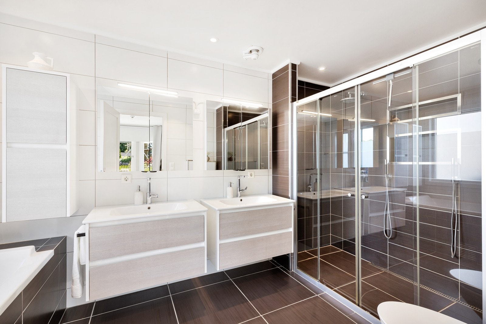 Flislagt bad med varme i gulv. Badet har badekar, dobbel dusj, dobbel servant og vegghengt toalett. Galleribilde