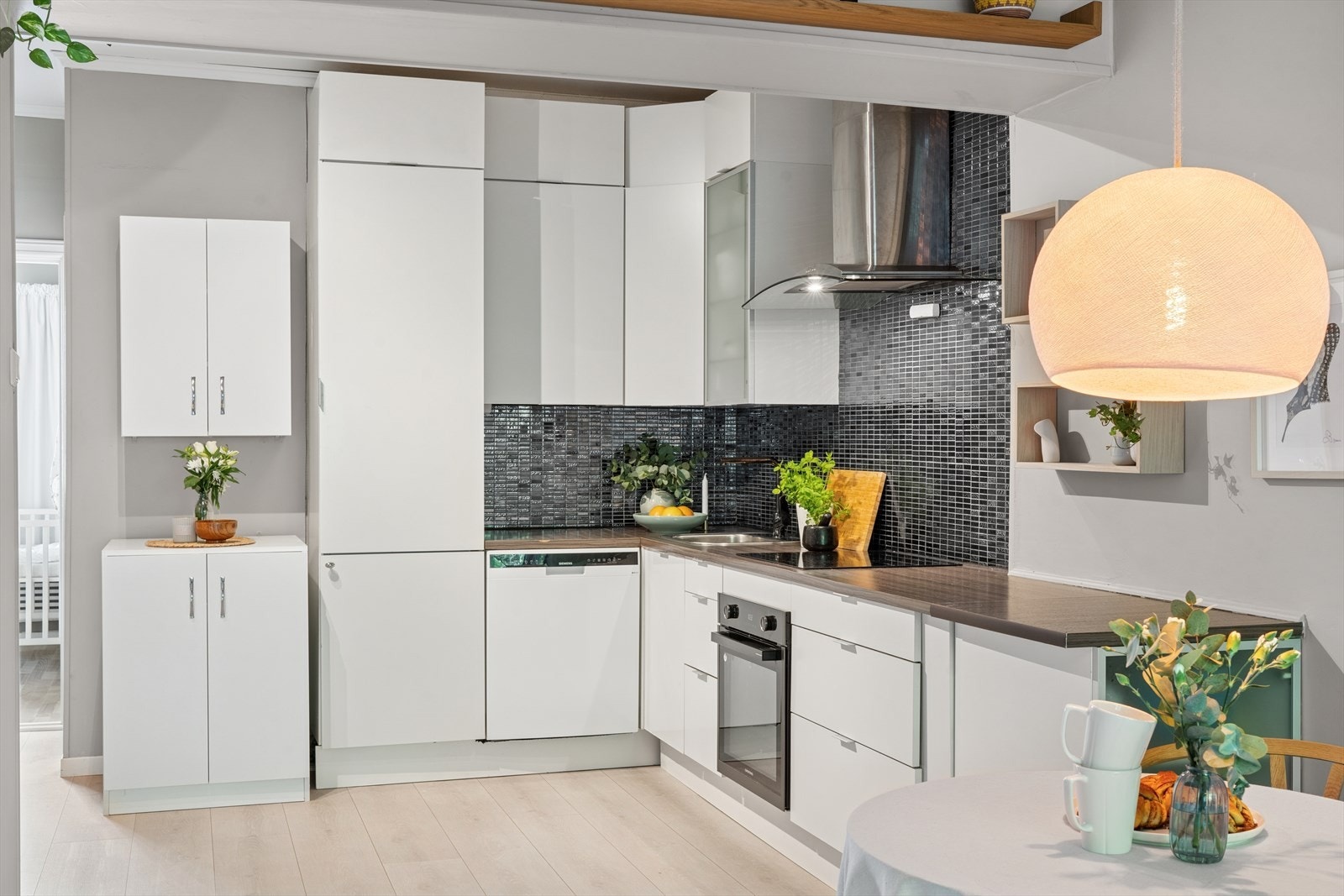 Kjøkkenet består av hvit, glatt innredning med god oppbevaringsplass. Det er integrert koketopp/ovn med komfyrvakt og kullfiltervifte montert over. Galleribilde