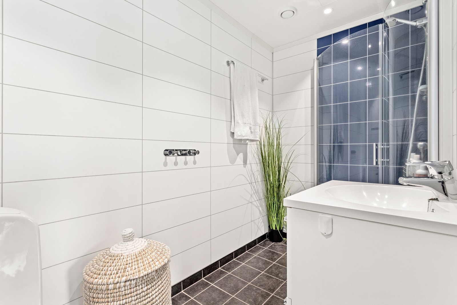 Badet er utstyrt med baderomsinnreiing, vegghengt toalett og dusjhjørne. Galleribilde