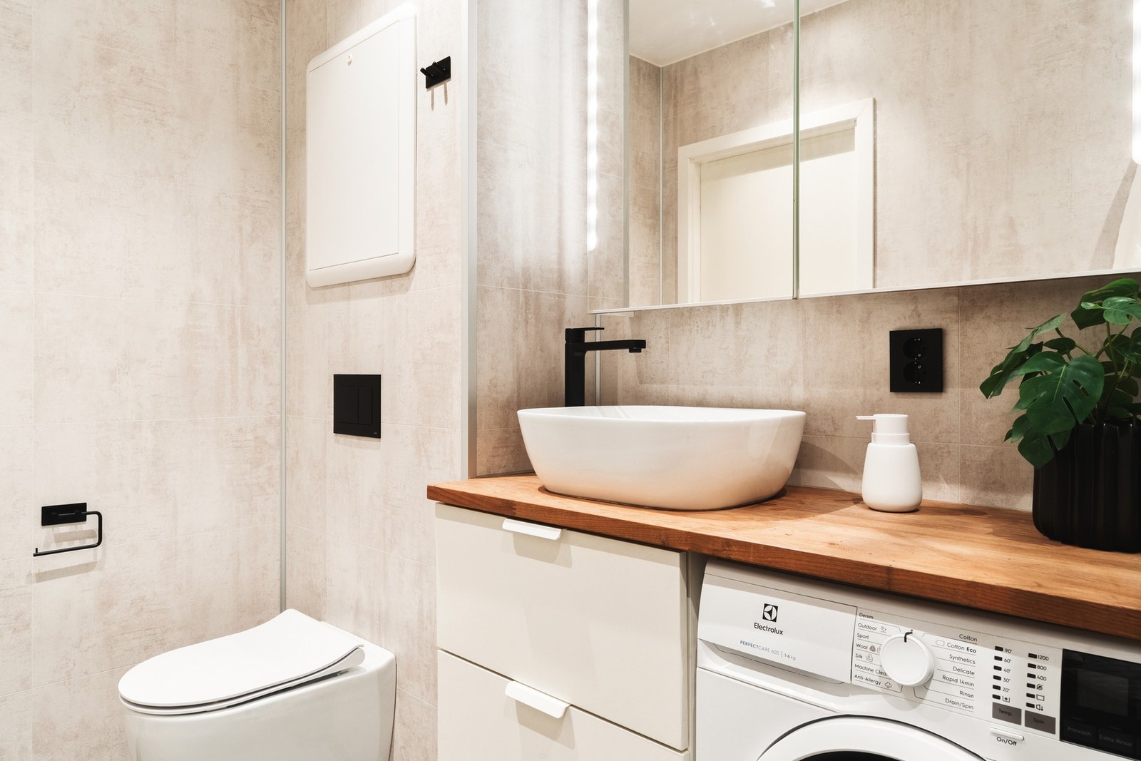 Rommet er innredet med dusj med glassvegg, vegghengt toalett, baderomsinnredning og opplegg for vaskemaskin. Galleribilde