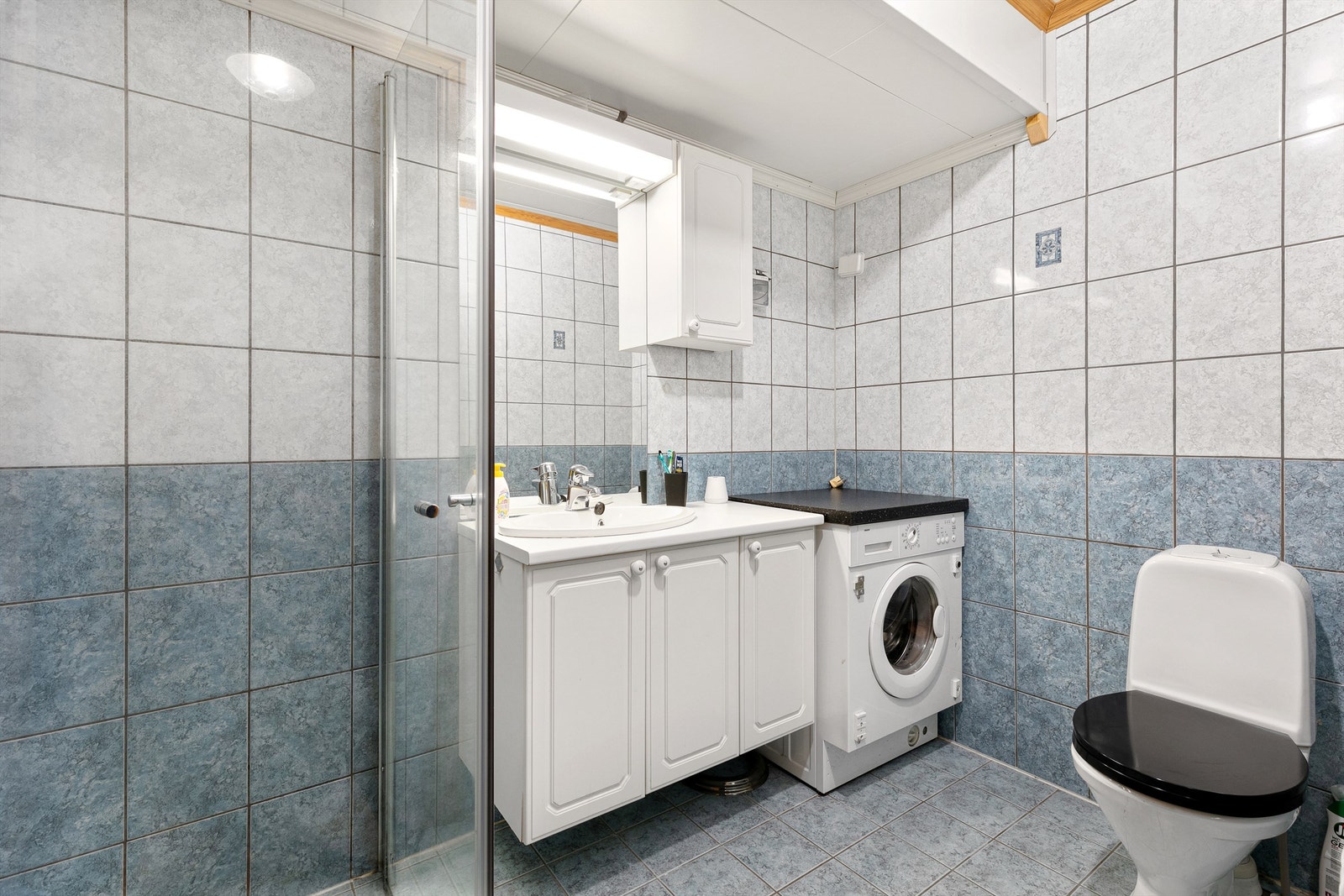 Badet i utleiedelen er flislagt på gulv og vegger, med dusj, wc og vask. Galleribilde