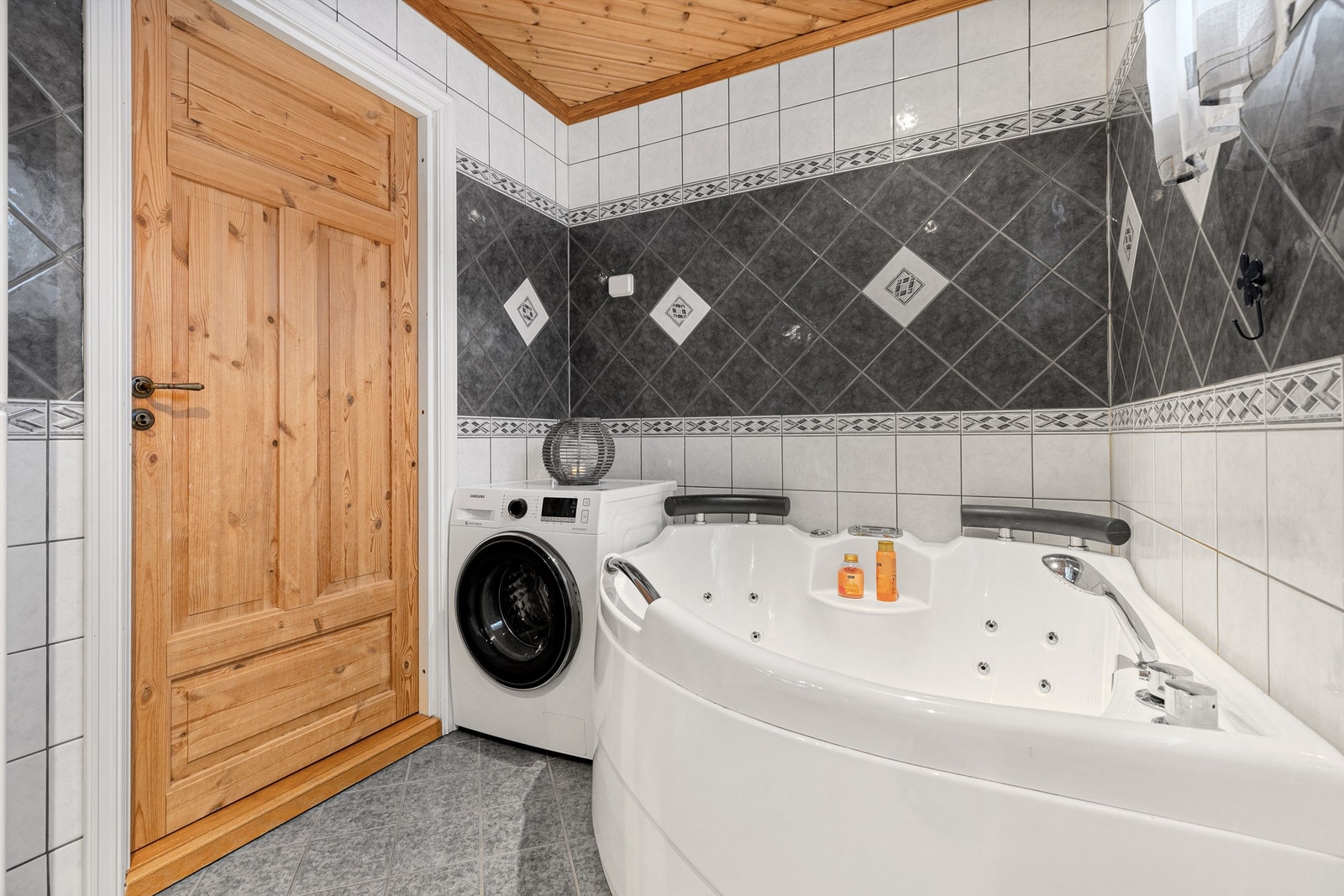 Hoved bade har flislagte gulv og vegger, med boblebadekar, vask, wc og opplegg vaskemaskin. Galleribilde