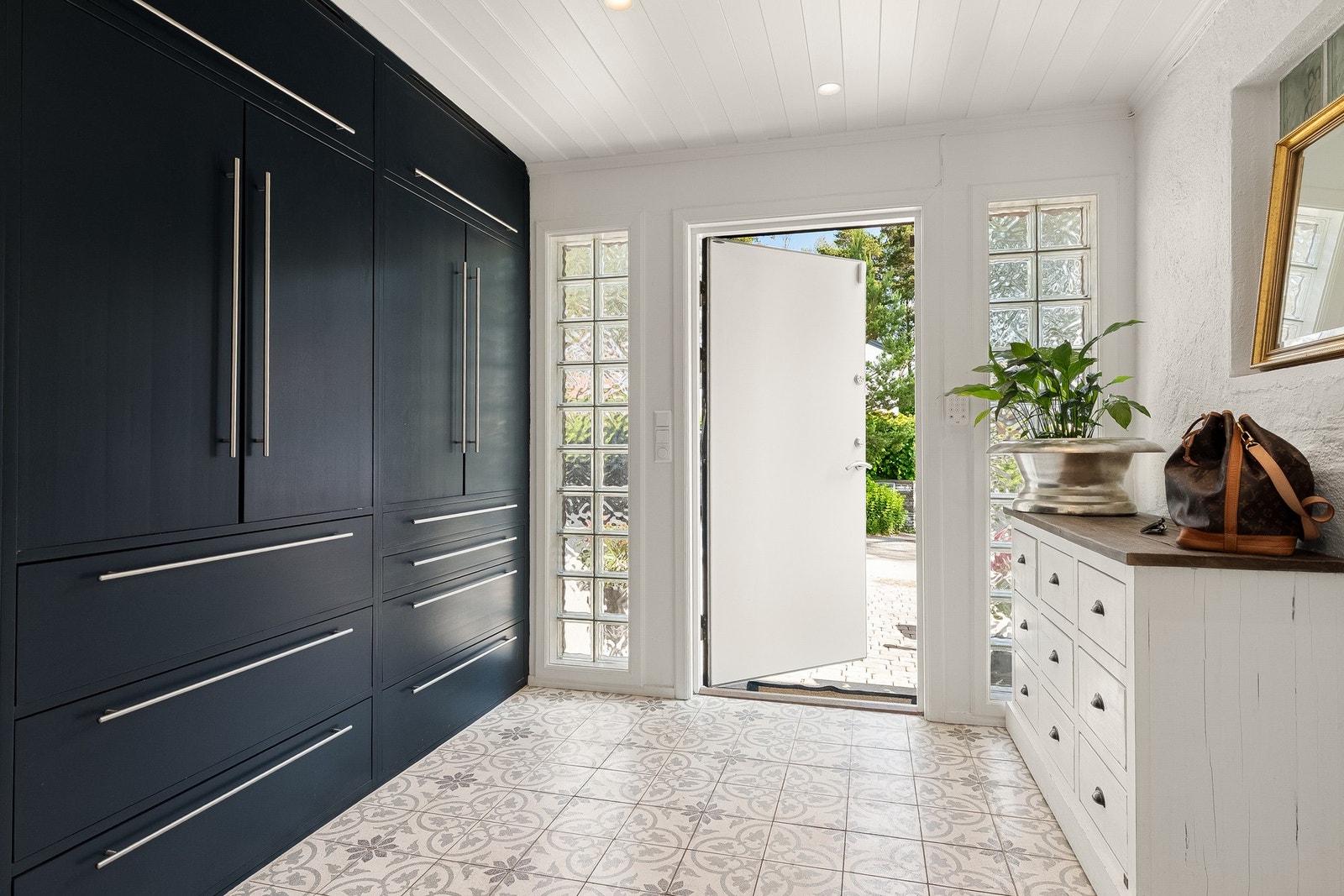 En romslig entré ønsker deg velkommen, med pene, historiske fliser og behagelig gulvvarme. Romslig, plassbygget garderobe gir mye lagringsplass for klær og sko Galleribilde