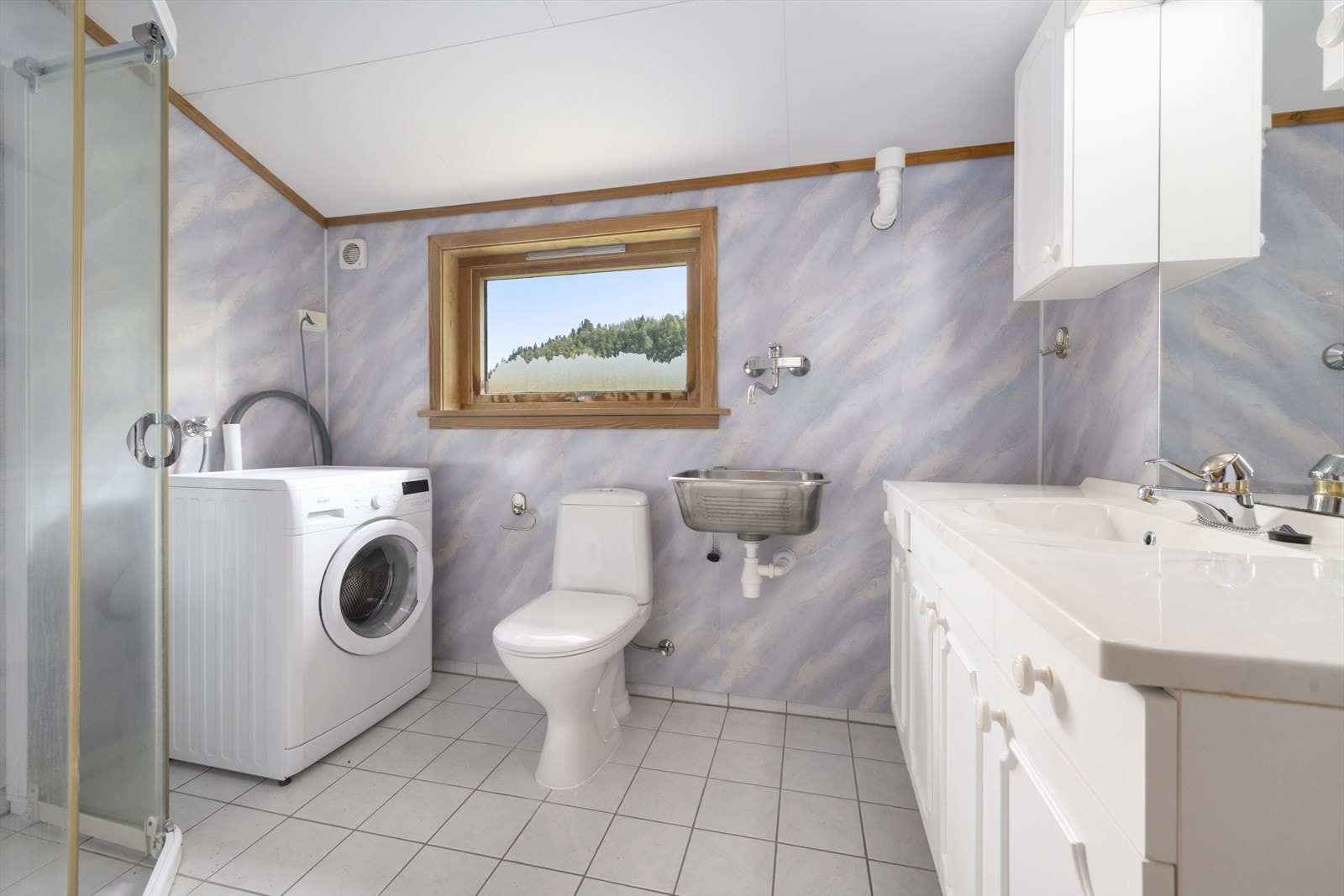 Badet har flislagt golv og baderomsplater på veggane. Opplegg for vaskemaskin Galleribilde