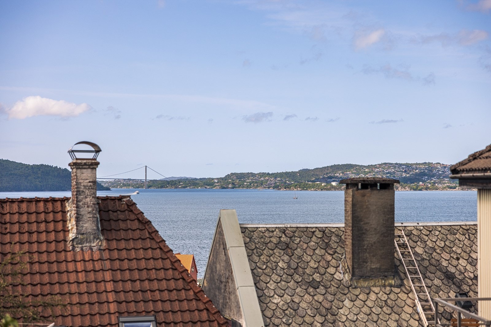 Spektakulær utsikt mot sjøen og fjellene, med sjarmerende hustak i forgrunnen. Perfekt beliggenhet for ro og naturopplevelser. Galleribilde