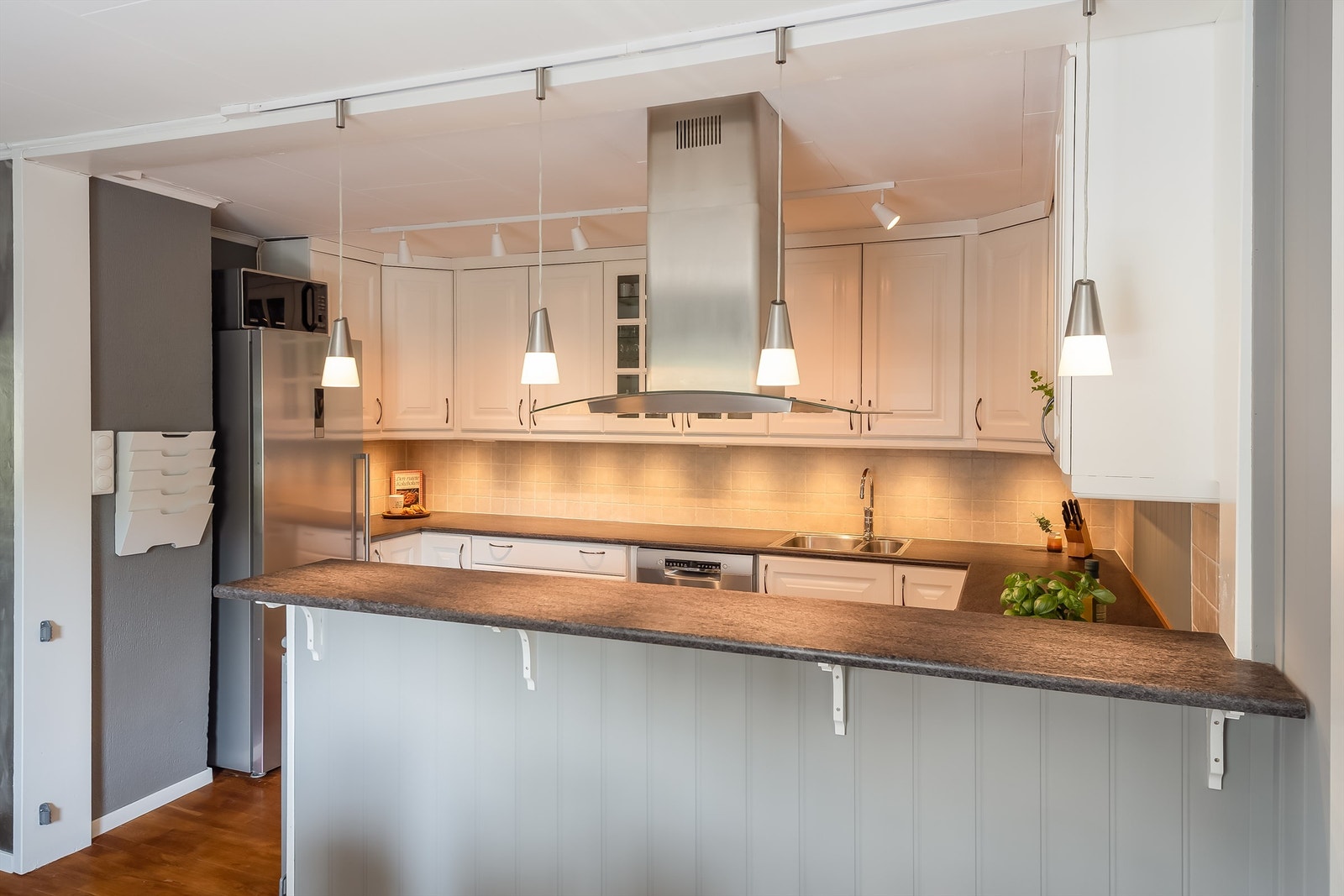 Flott åpen løsning med en praktisk kjøkkenøy som også gir skjerming mot kjøkkenet. Rikelig med skap- og benkeplass Galleribilde