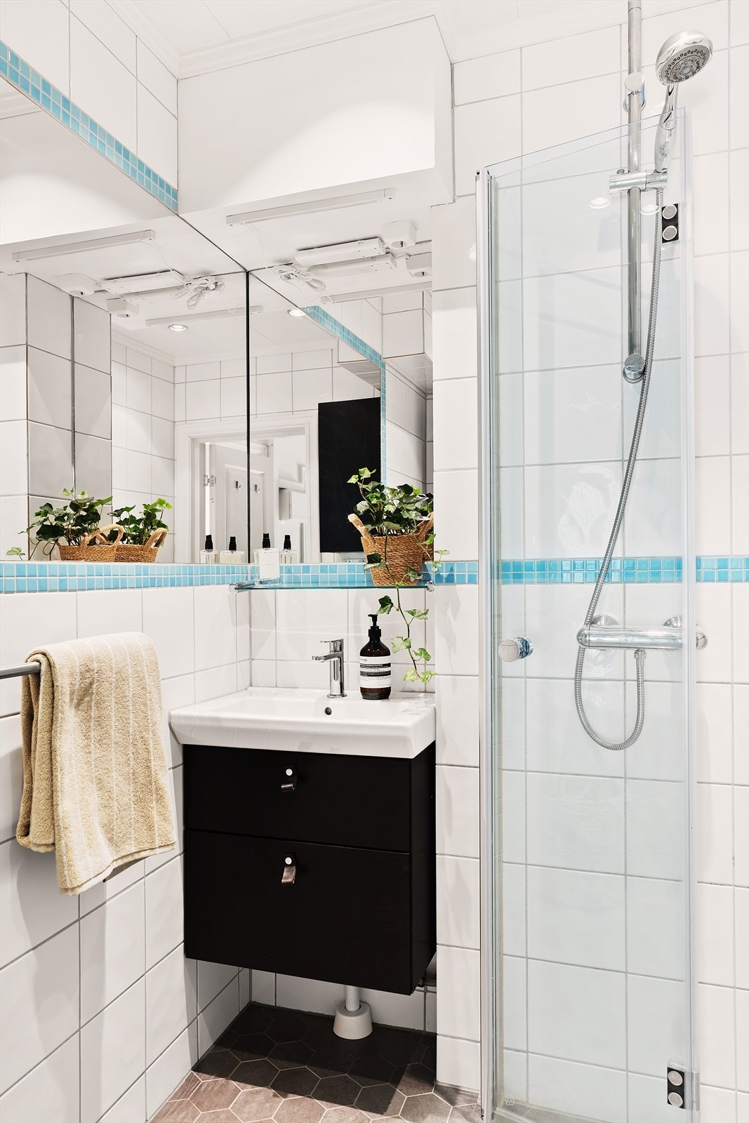Badet har downlights i himling, vegghengt servantskap med ett-greps armatur, vegghengt speil med overbelysning og dusjhjørne med innfellbare glassdører og to-greps armatur påkoblet hånddusj. Galleribilde