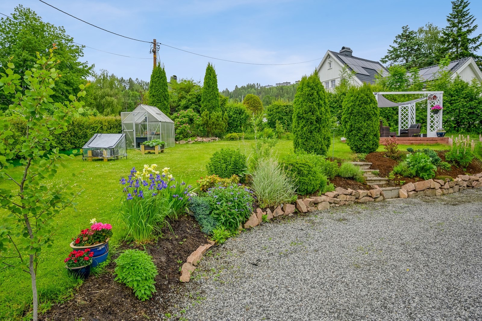 Meget pent opparbeidet tomt med drivhus og pergola. Galleribilde