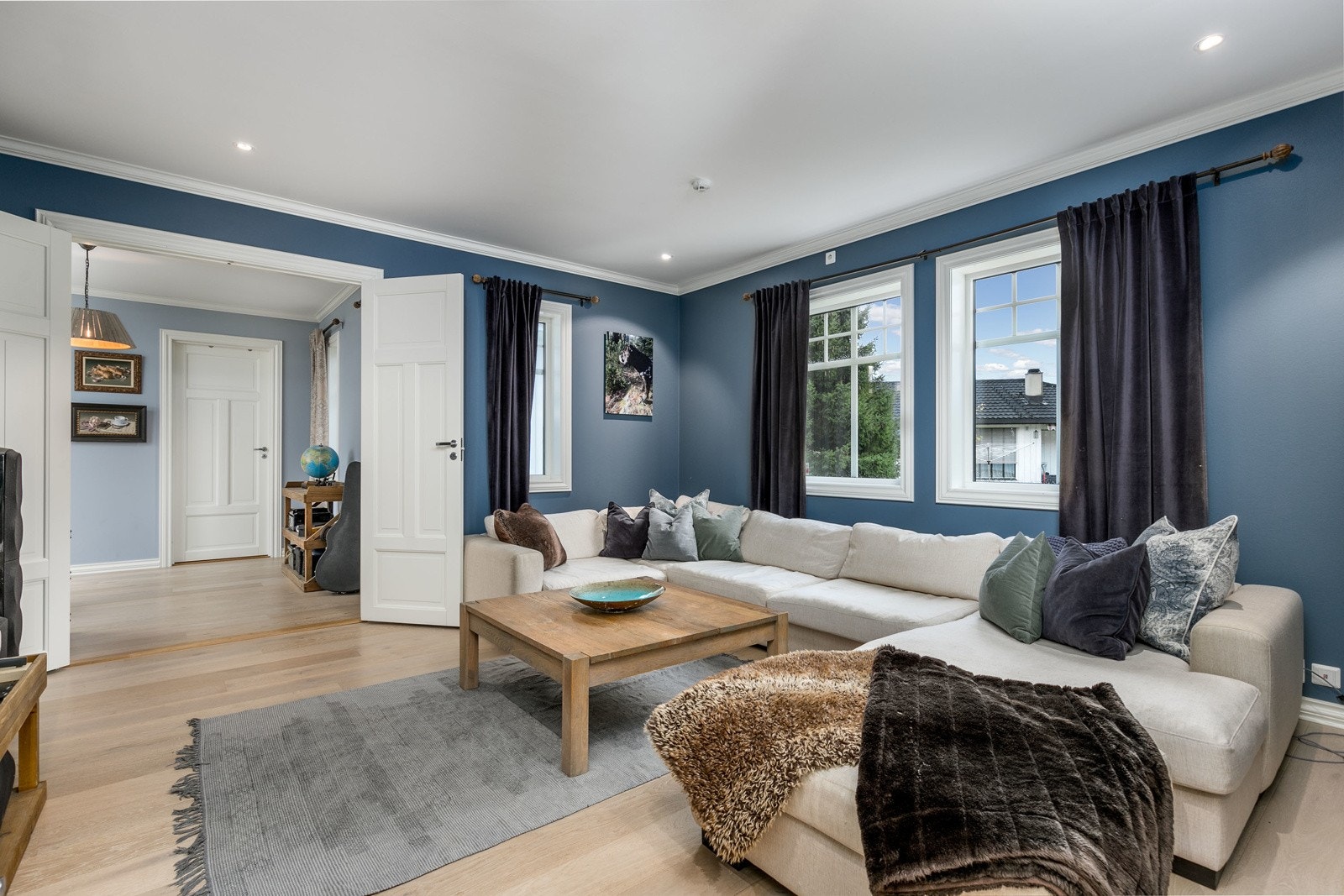 Koselig Tv-stue i boligens 1. etasje med malte slette veggflater og enstavs lyspigmentert parkett på gulv med vannbåren gulvvarme. Her er det god plass til sofaløsning med tilhørende møblement. De store vinduene slipper inn rikelig med lys. Galleribilde