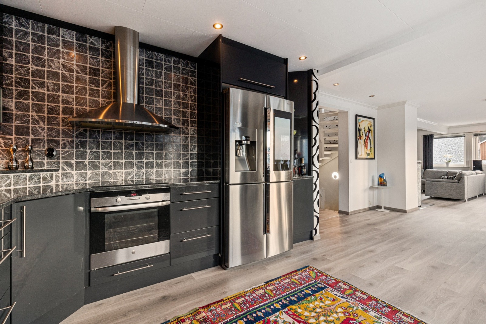 Den åpne løsningen mellom stue og kjøkken gir rom for flere sosiale soner selv ved matlaging Galleribilde