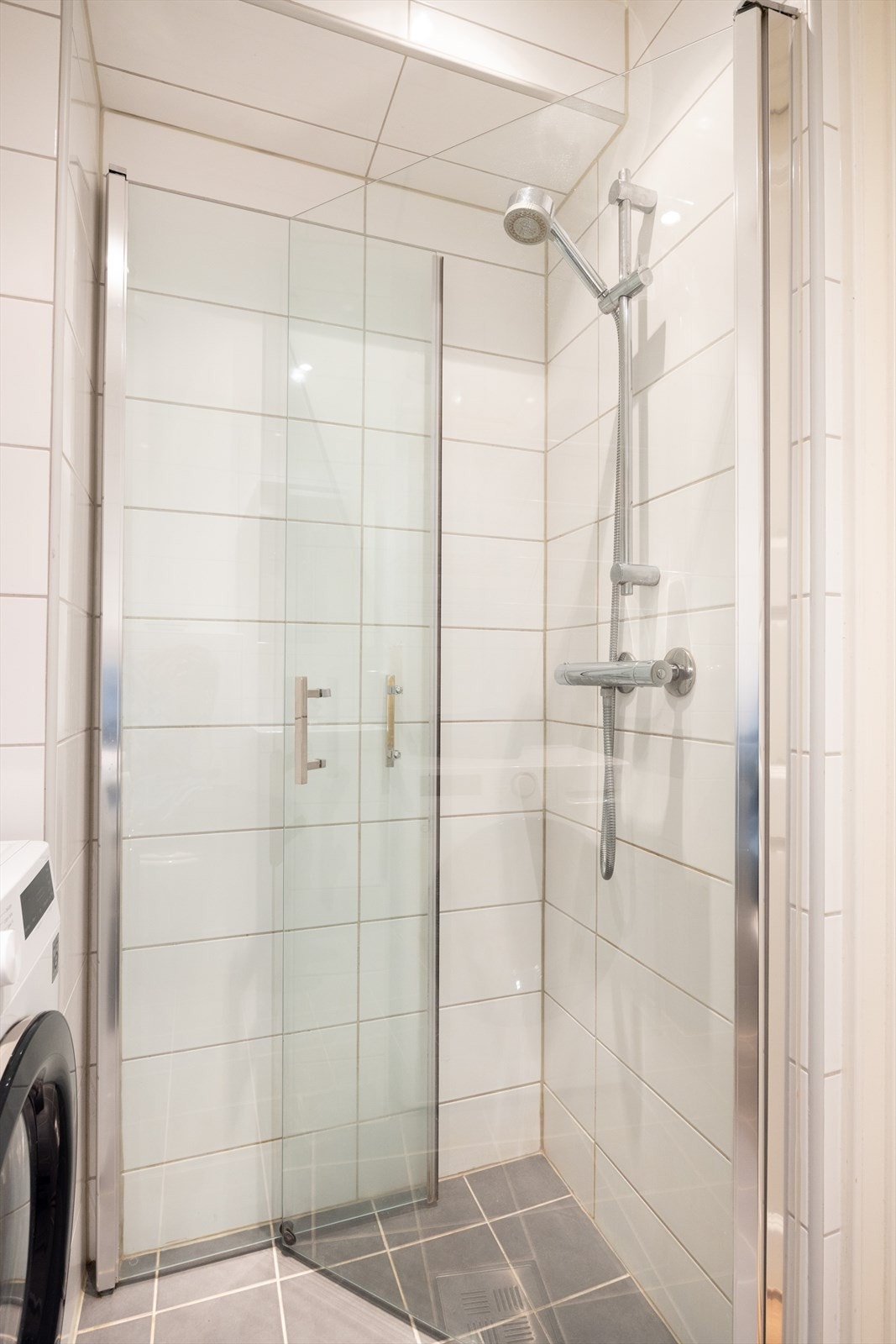 Inneholder blant annet grå 20x20 fliser på gulv, hvite 20x50 fliser på vegger og gips-himling med downlight. Galleribilde