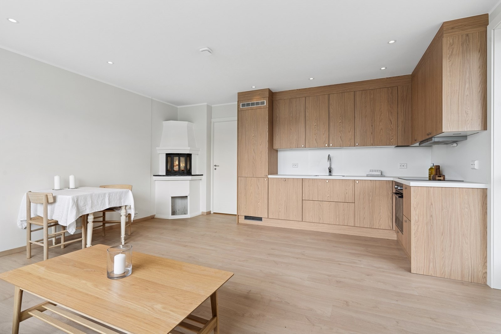 Åpen stue og kjøkkenløsning med peis i hjørnet Galleribilde