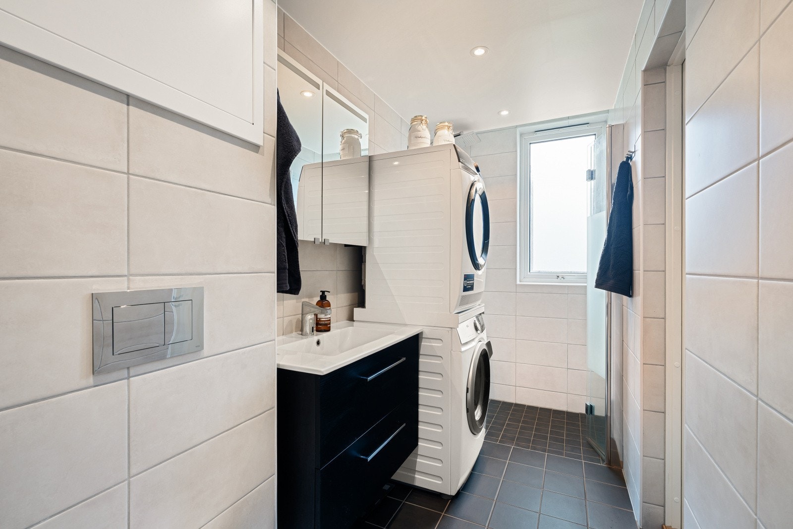 Moderne baderomsløsning med: dusjhjørne, vaskemaskin, servant og vindu for lys og luft. Galleribilde