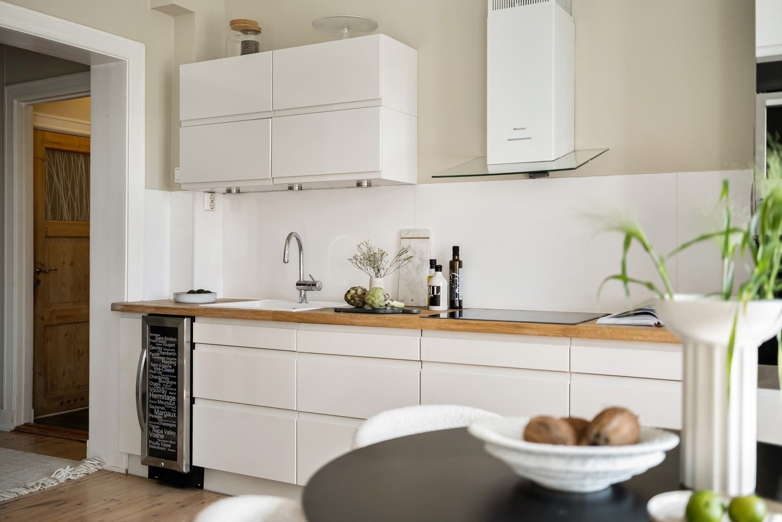 Moderne kjøkkeninnredning med glatte fronter, heltre benkeplate med nedfelt vaskekum, samt plate og belysning over benkeplaten. Galleribilde