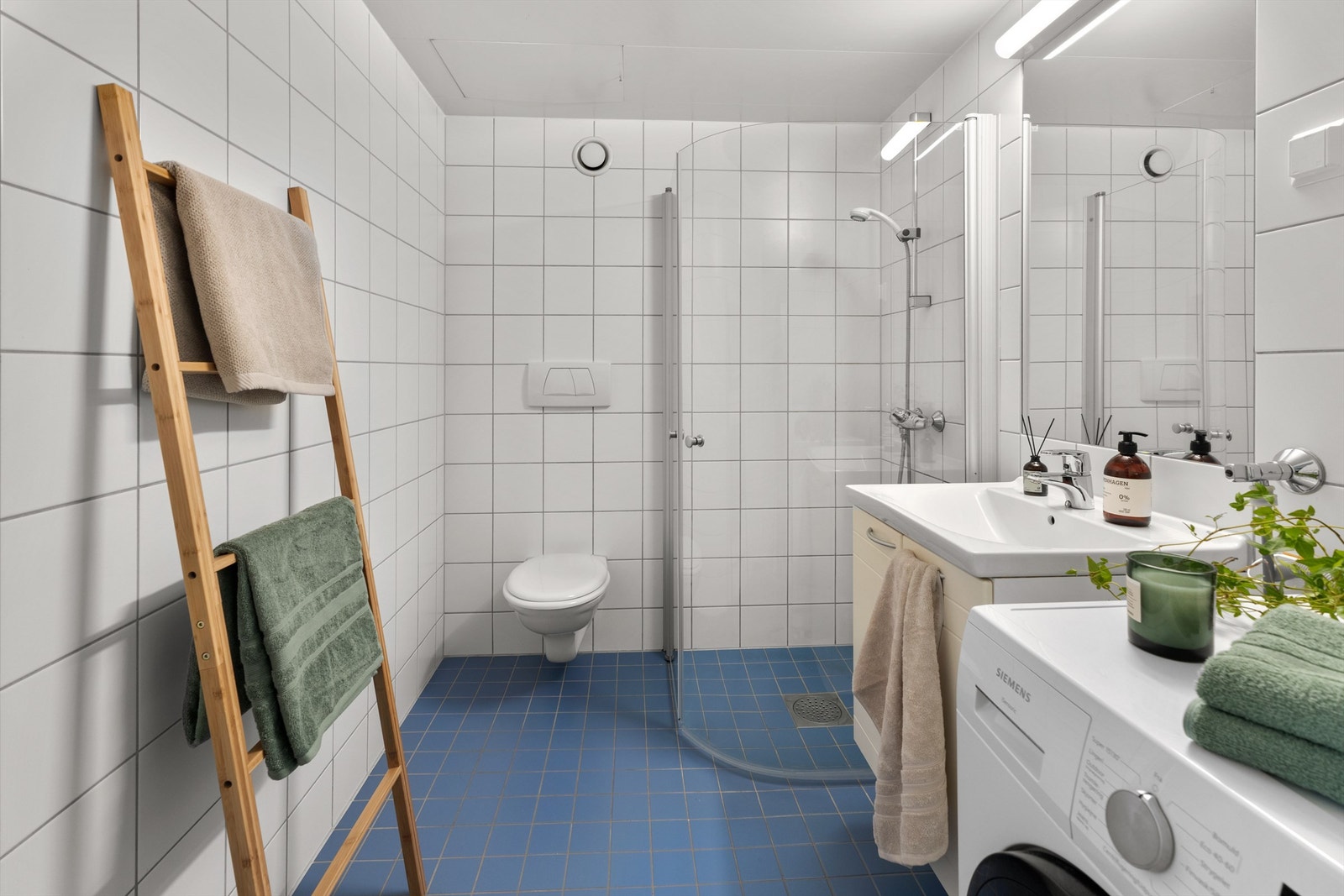 Badet har vegghengt servantinnredning med dører, ovenpåliggende servant med ett-greps armatur samt speil med overlys og stikkontakt over servant. Galleribilde