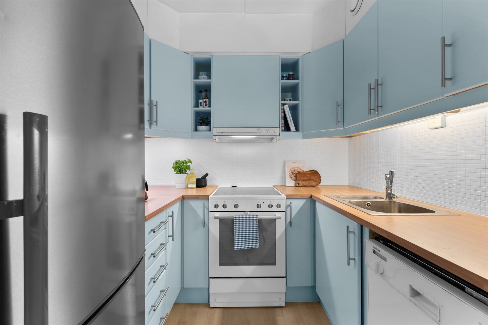 Kjøkkenet er utstyrt med frittstående komfyr, oppvaskmaskin under kjøkkenbenk, frittstående kjøleskap med fryser samt ventilator i overskap Galleribilde