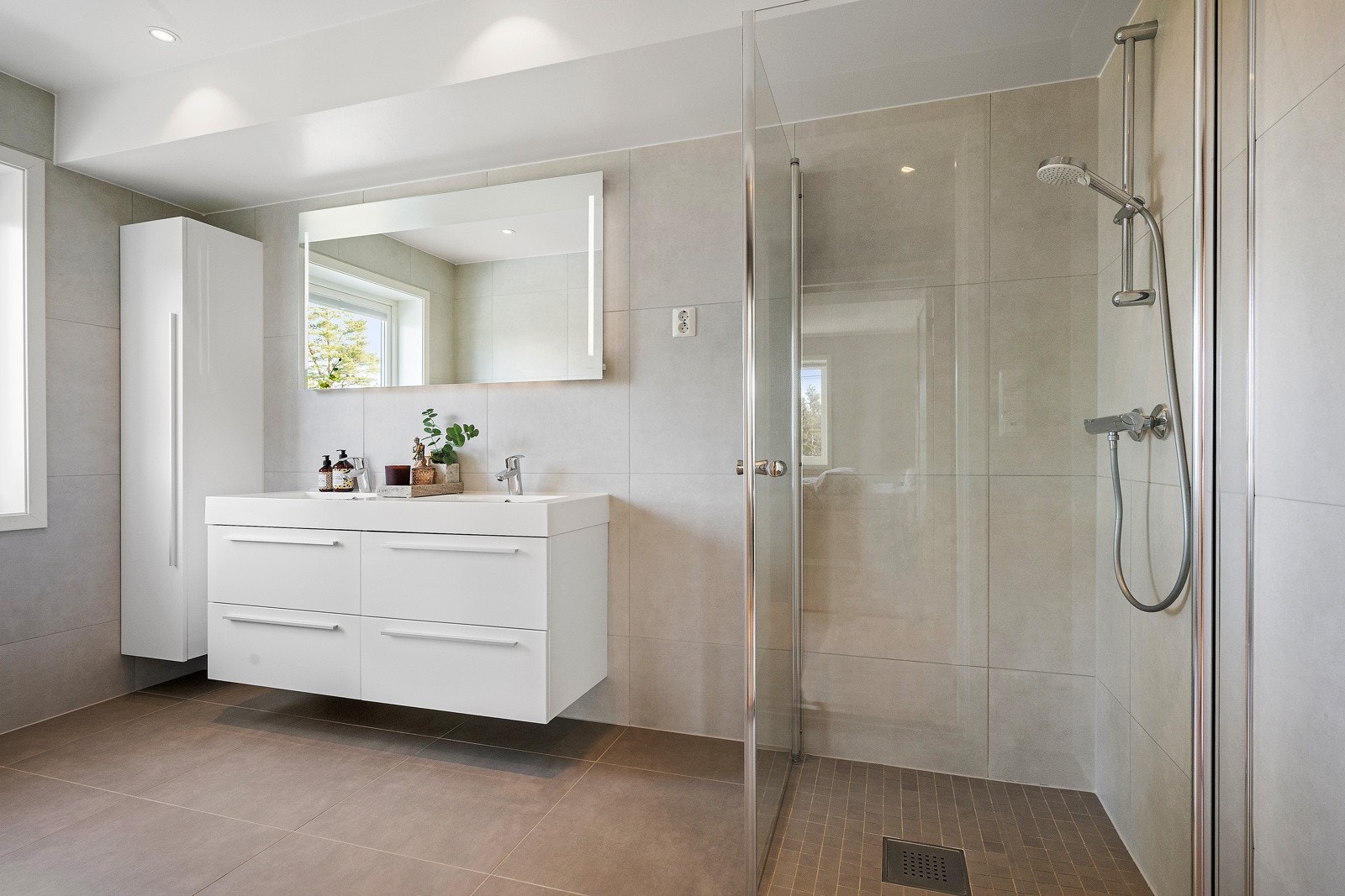 Delikat baderom med store fliser på vegger og gulv, varmekabler, downlights og balansert ventilasjon. Galleribilde