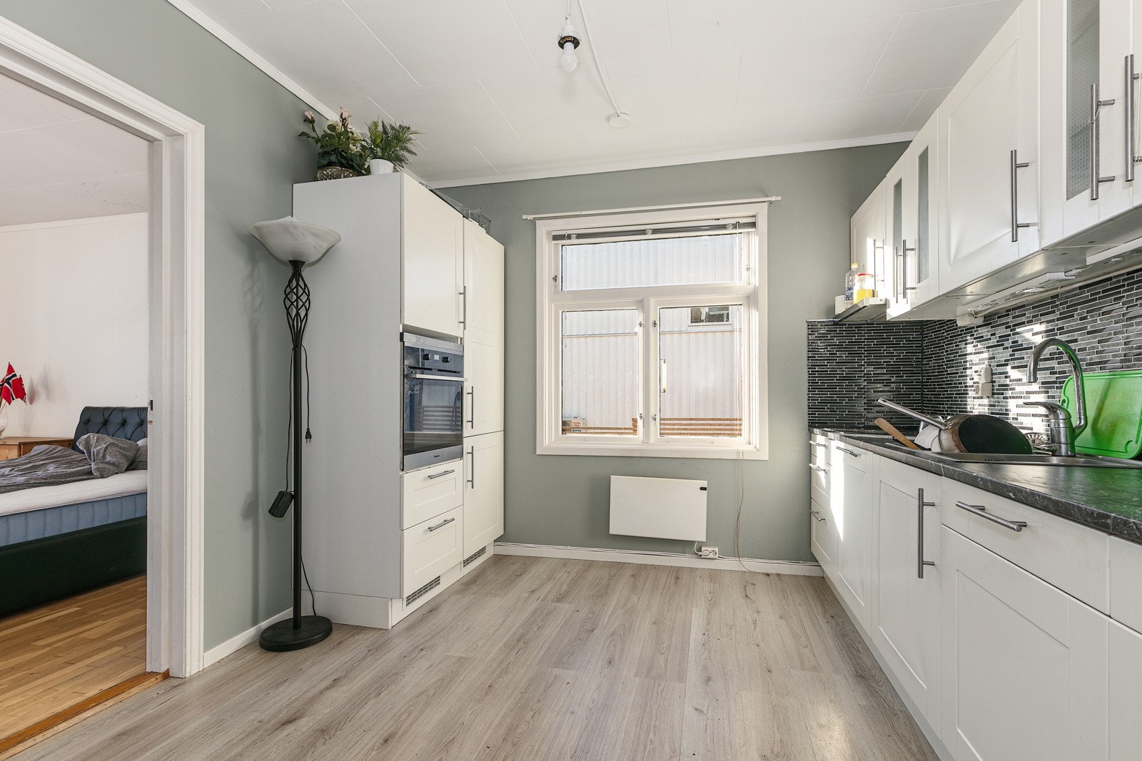 Lyst kjøkken med mye skap og benkeplass. Galleribilde