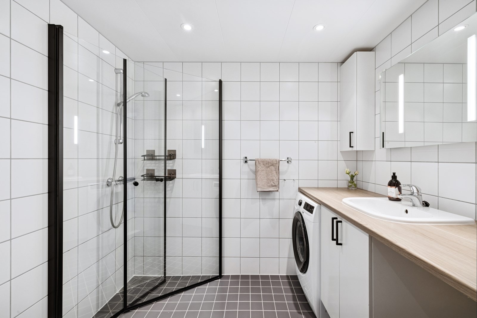 Romslig bad med opplegg for både vaskemaskin og tørketrommel under benkeplate. Galleribilde
