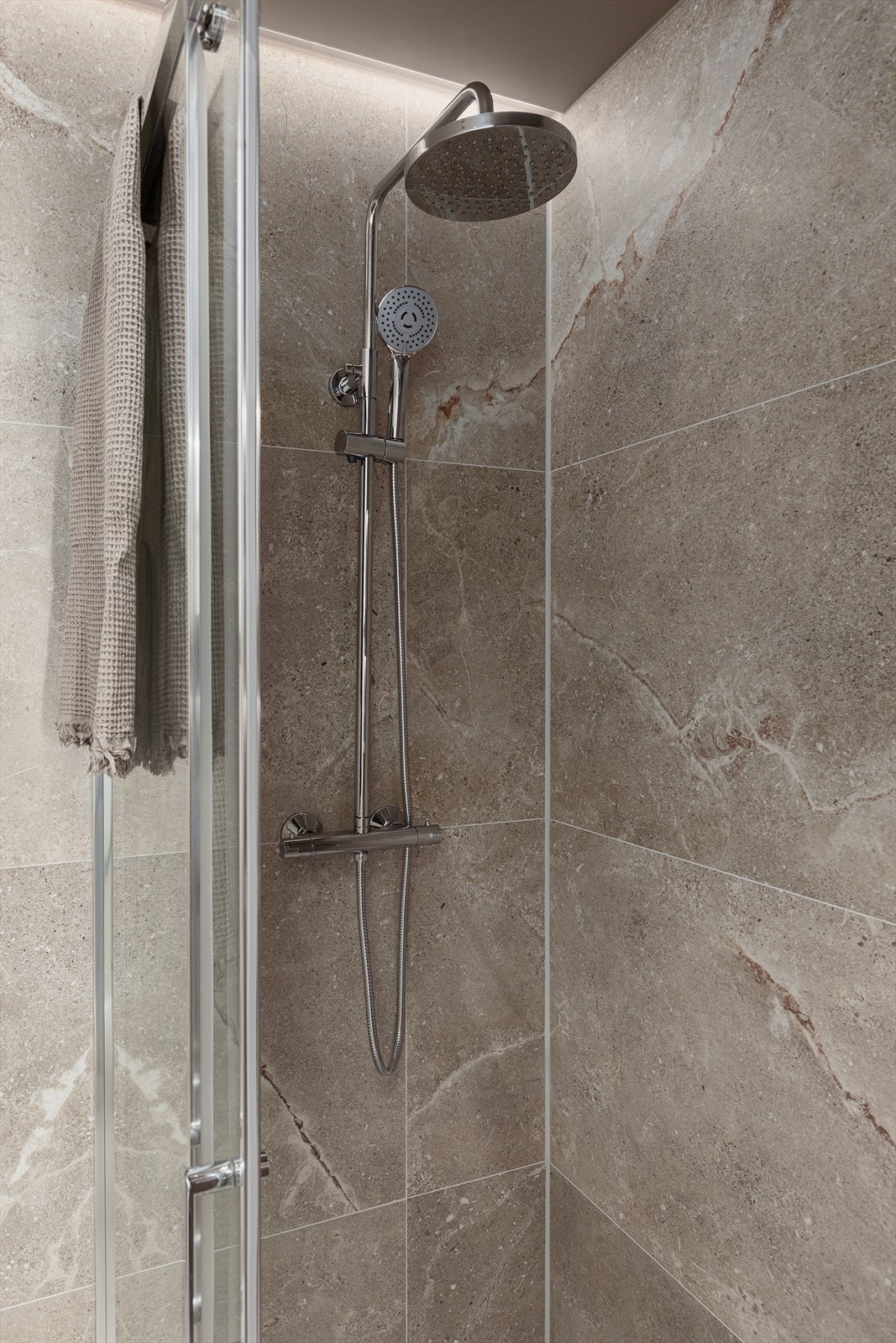 Badet består av dusjvegger i glass, armaturer i krom, vegghengt toalett, fuktstyrt vifte, varmekabler i gulv og downlights + led i tak. Galleribilde