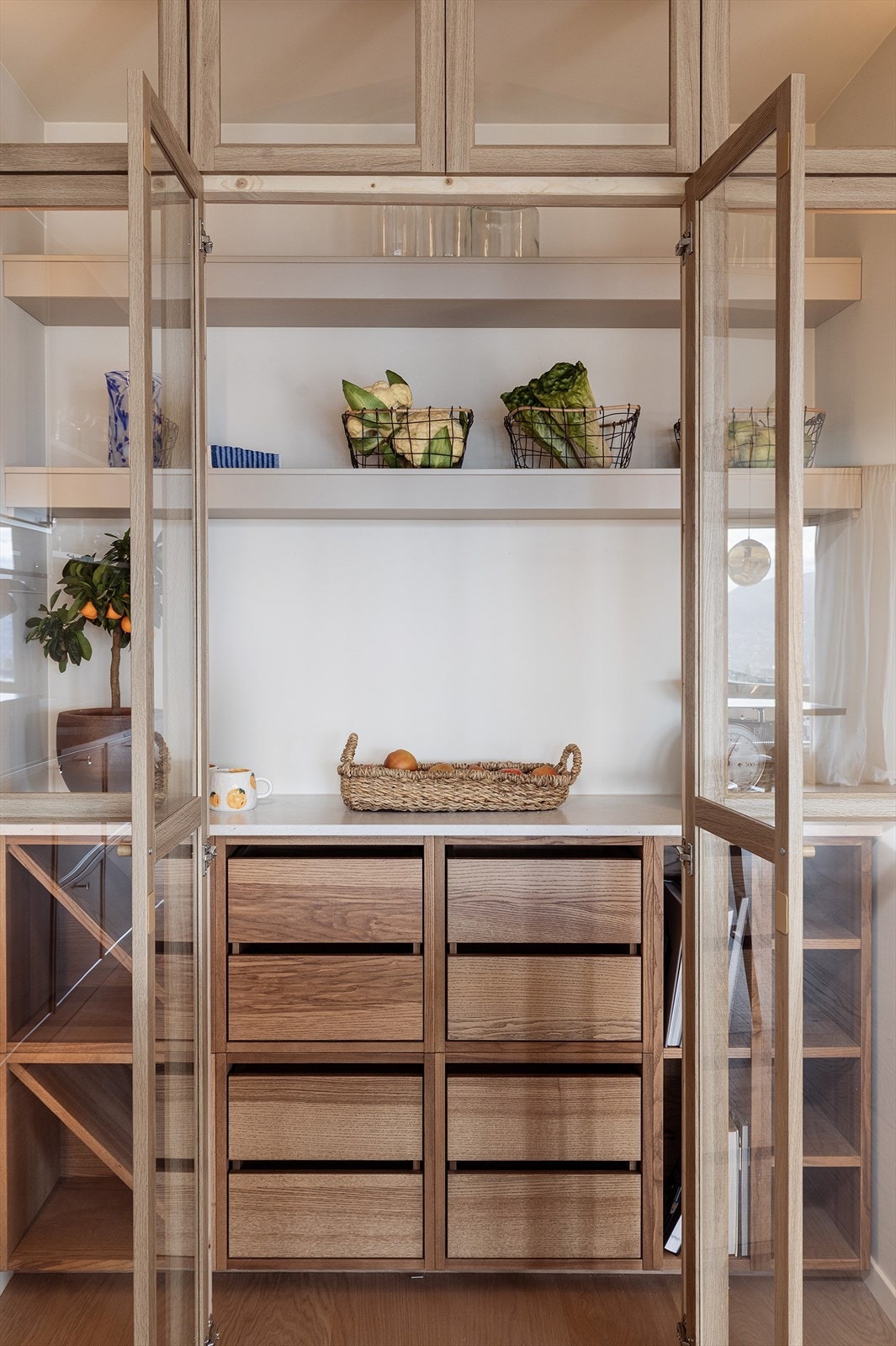 Innebygd pantry i enden av kjøkkenet med god oppbevaring. Utført med vitrinedører og møblement i lun tre-utførelse. Belyst med LED. Galleribilde