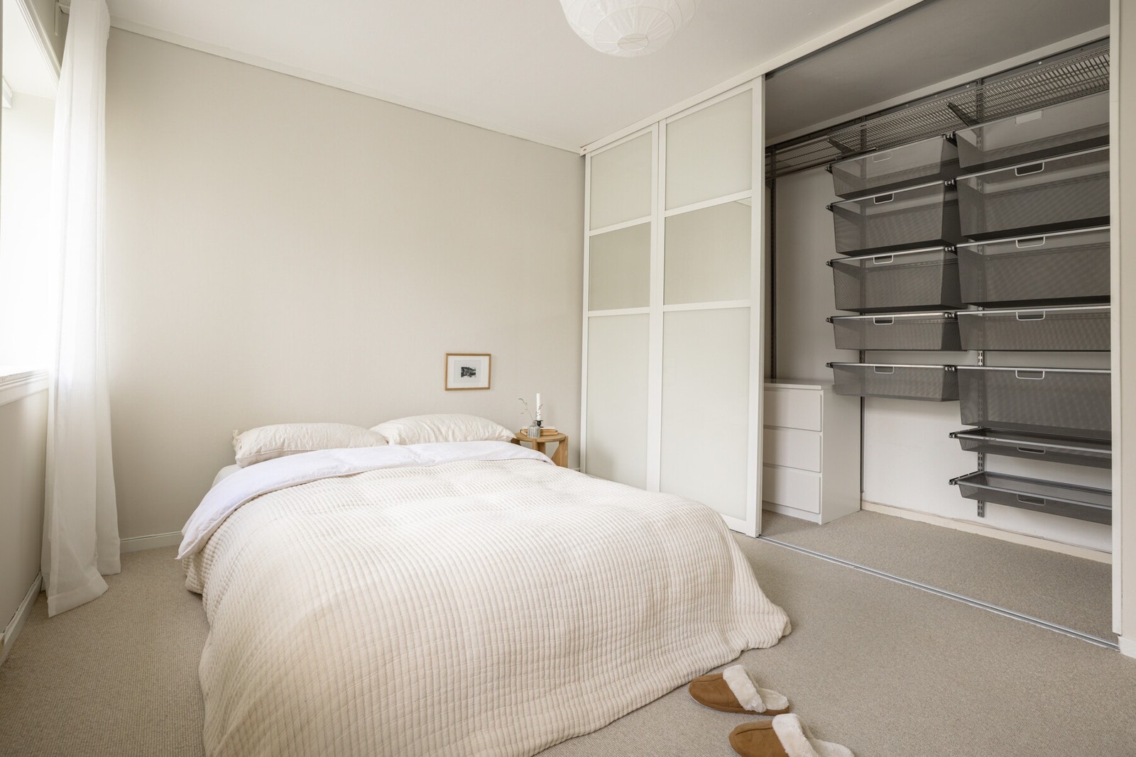 Walk-in garderobe innredet med klesoppheng, hyller, trådkurver, kommoder og gulvplass. Galleribilde