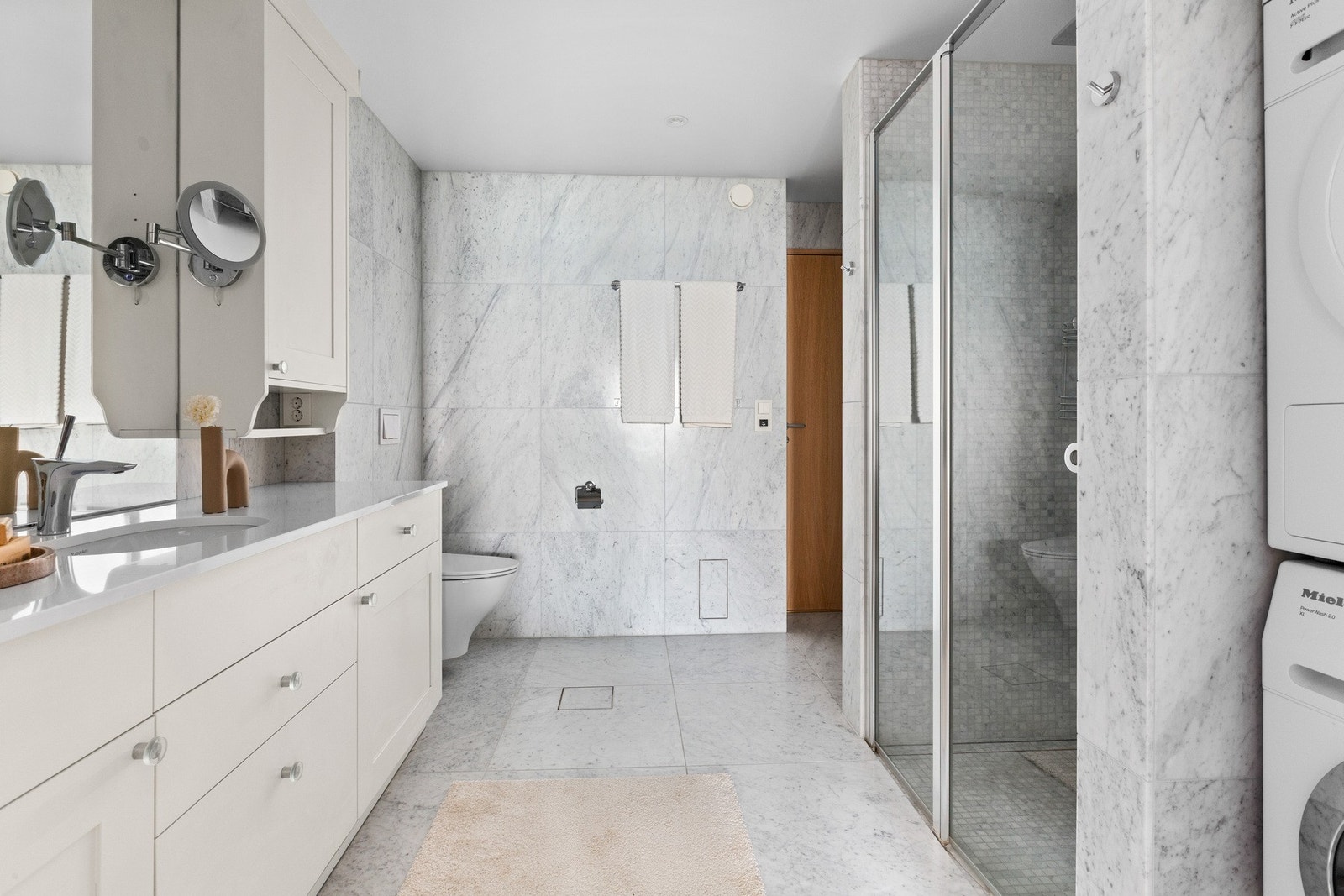 Vegger og gulv er flislagt med marmor, og dusjsonen har mosaikkfliser. Galleribilde