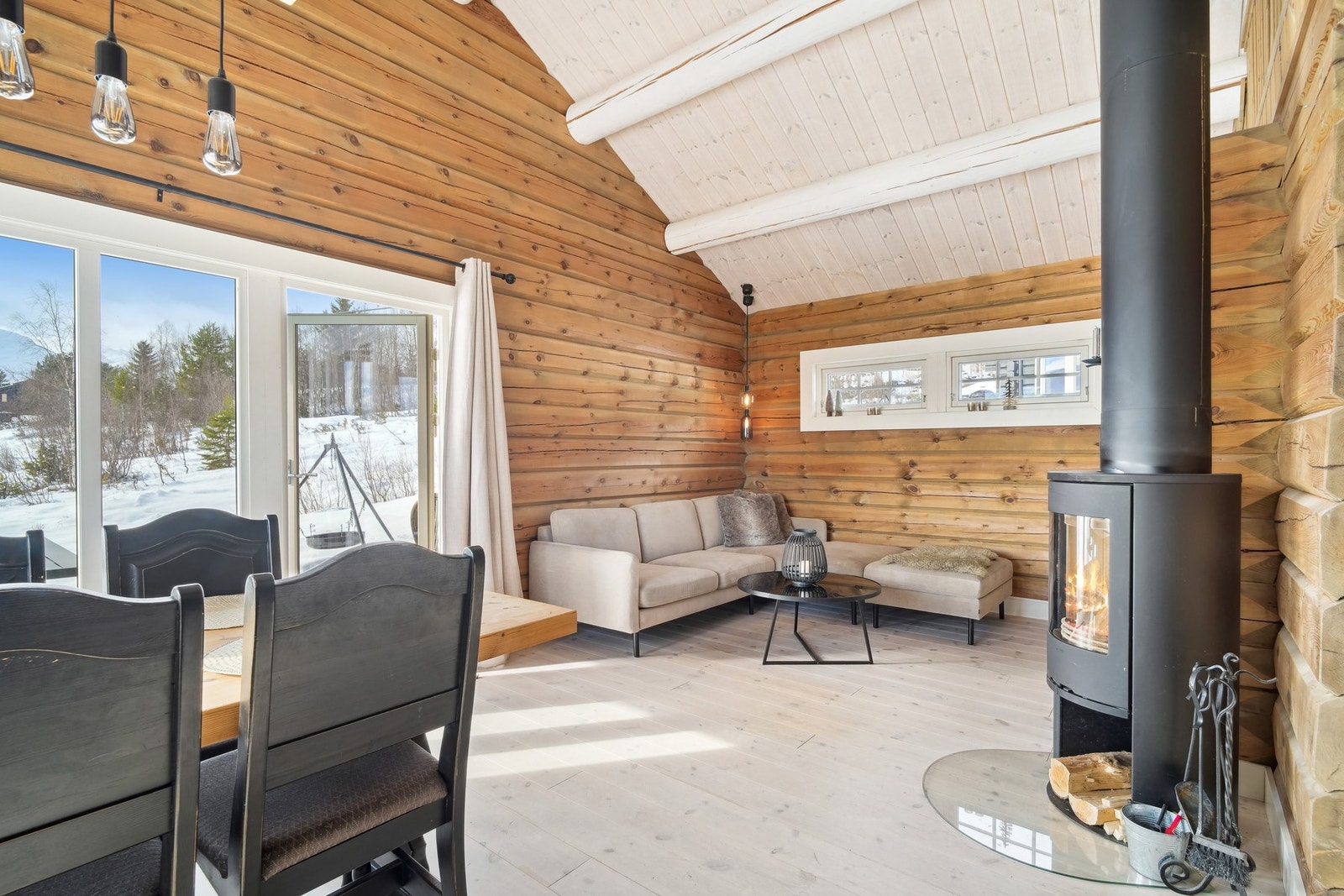 Åpen stue/kjøkken-løsning på 28,5 kvm med tømmer på vegger og furugulv. Galleribilde