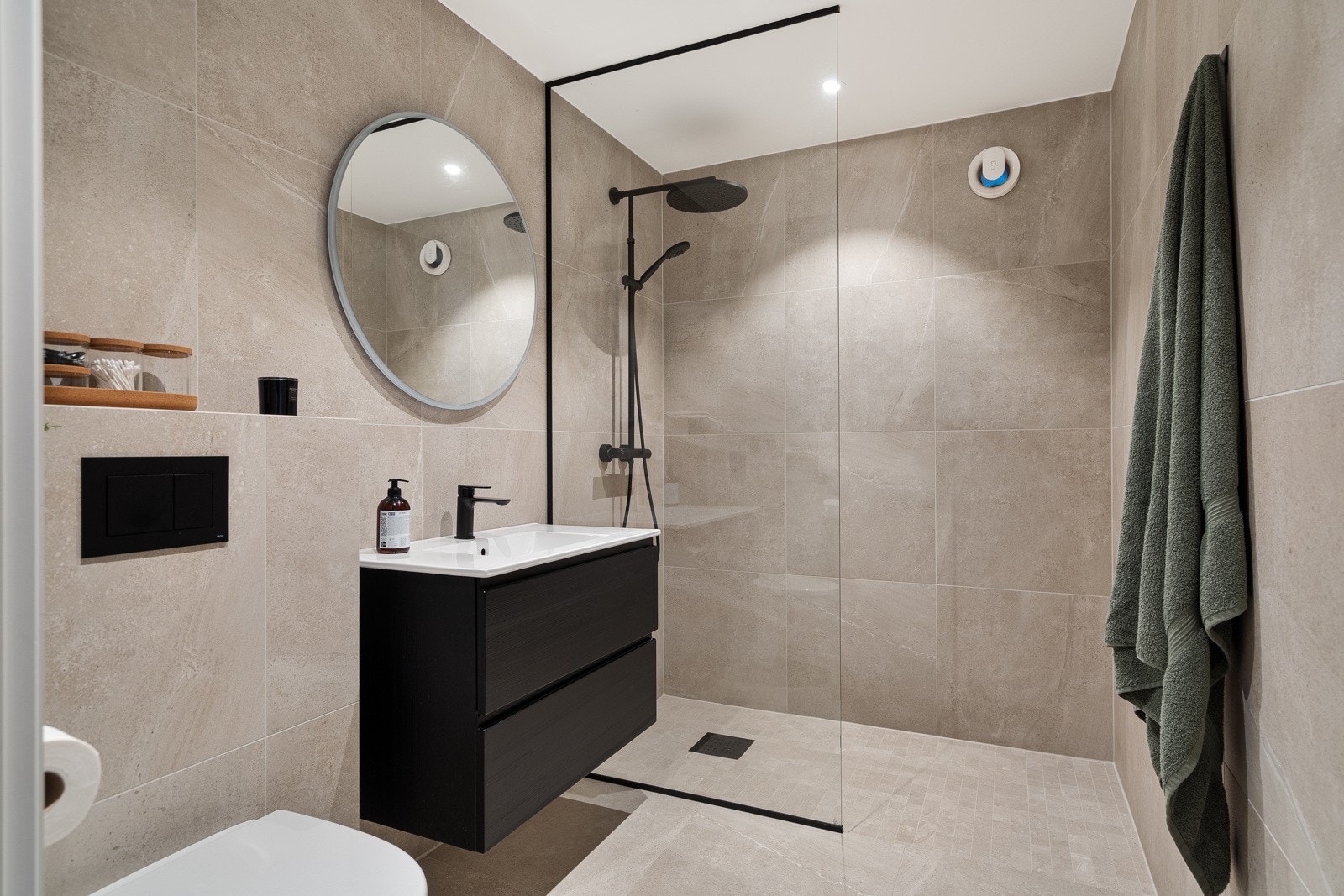 Badet er elegant innredet med stilfulle fliser i tidsriktige 60x60-formater og en gjennomført innredning som inkluderer servant, vegghengt wc og en praktisk dusjnisje. Dette skaper et både funksjonelt og estetisk tiltalende rom. Galleribilde