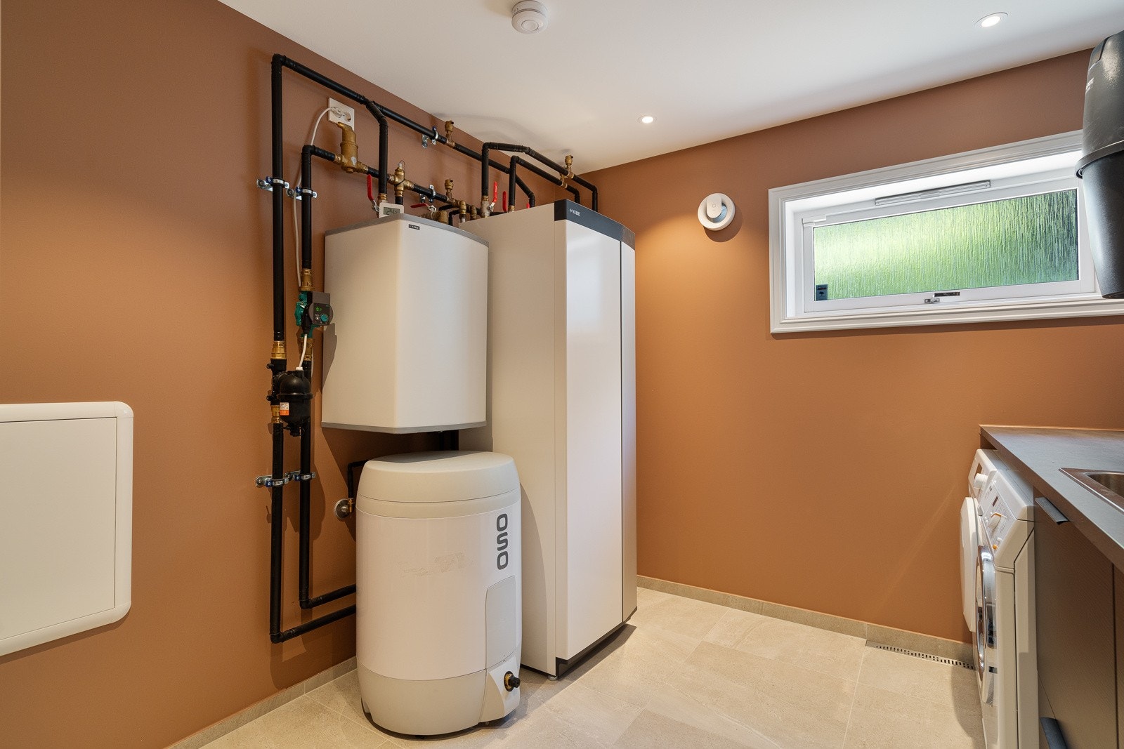 Teknisk installasjon av en luft-til-vann-varmepumpe, som gir effektiv oppvarming og betydelige energibesparelser for boligen. Dette systemet sikrer både et behagelig inneklima og lavere energikostnader. Galleribilde