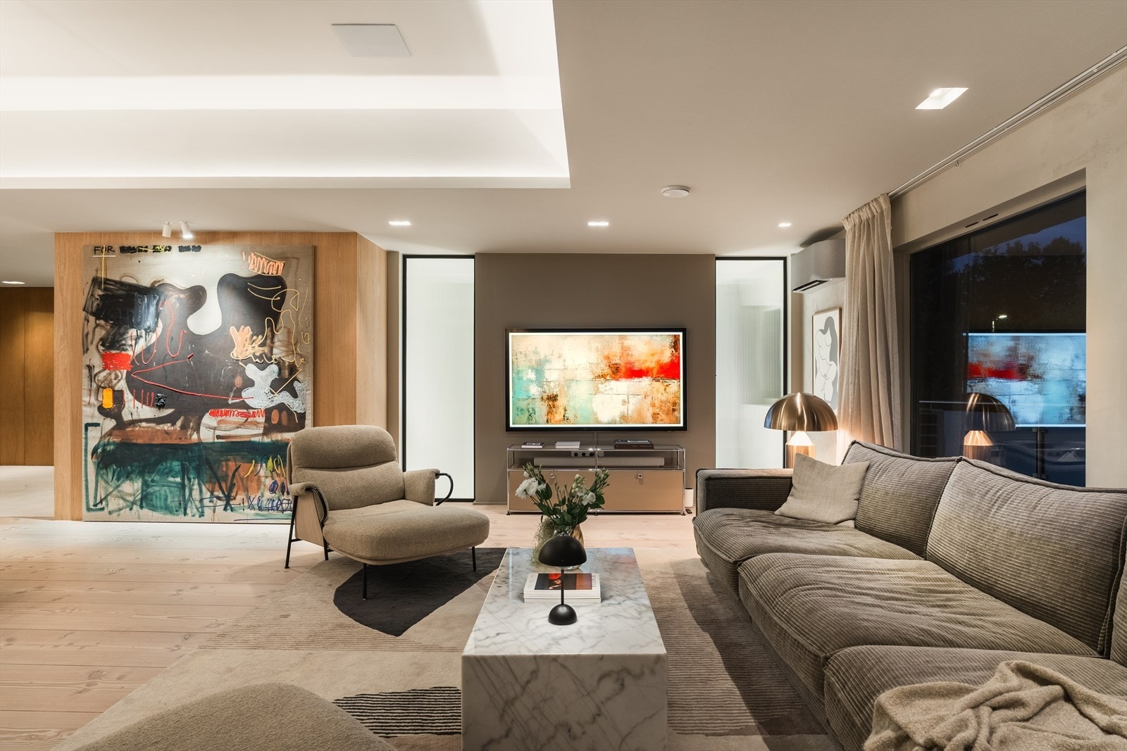 TV-veggen er innrammet av to gulv-til-tak glassflater i rillet herdet glass med pendellampe på baksiden for behagelig indirekte lys. Legg merke til varmepumpe med aircondition i pent design øverst til høyre i bildet. Galleribilde