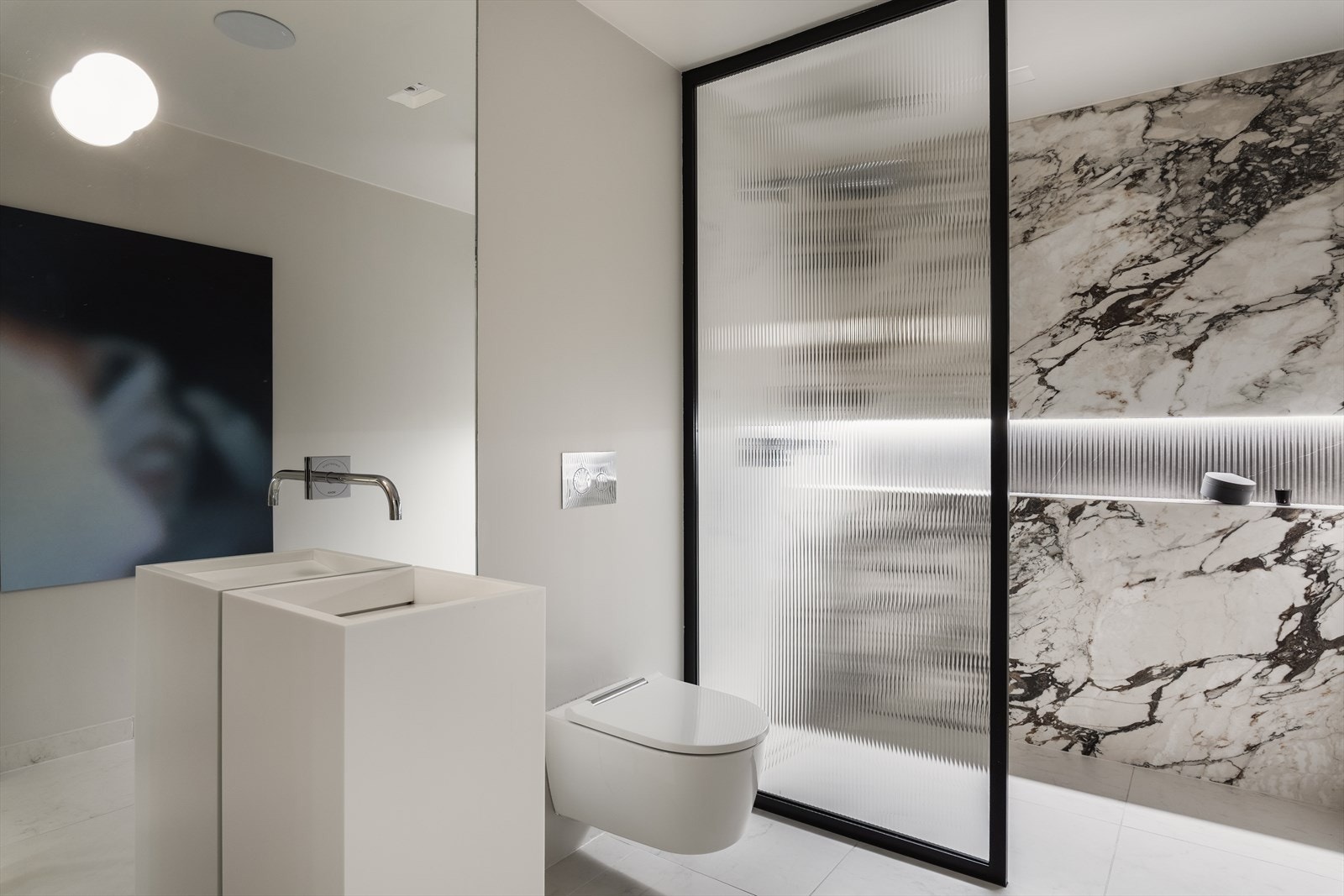 Gjestebad med spesialdesignet servant i Corian, Marazzi fliser, innfelt LED-belysning og Focal Custom stereo høyttaler i himling, tilknyttet egen separat Sonos AMP. Galleribilde