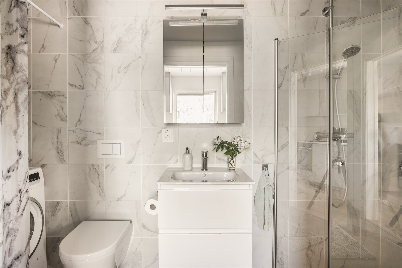 Pent flislagt bad. God størrelse og effektivt innredet med plass for fullverdig vaskemaskin, innredning, speilskap og servant, samt god dusjnisje. Galleribilde