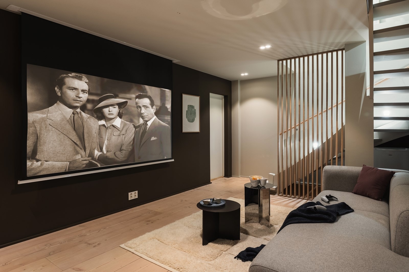 Kjellerstue innredet som filmrom med Dinesen-gulv og mørke veggflater. Trapp med eikespiler og integrert LED-belysning i trinnene. Galleribilde