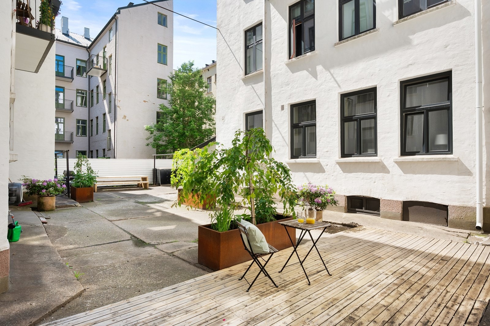 Hyggelig bakgård opparbeidet med platting, sittegrupper og pen beplantning. Galleribilde