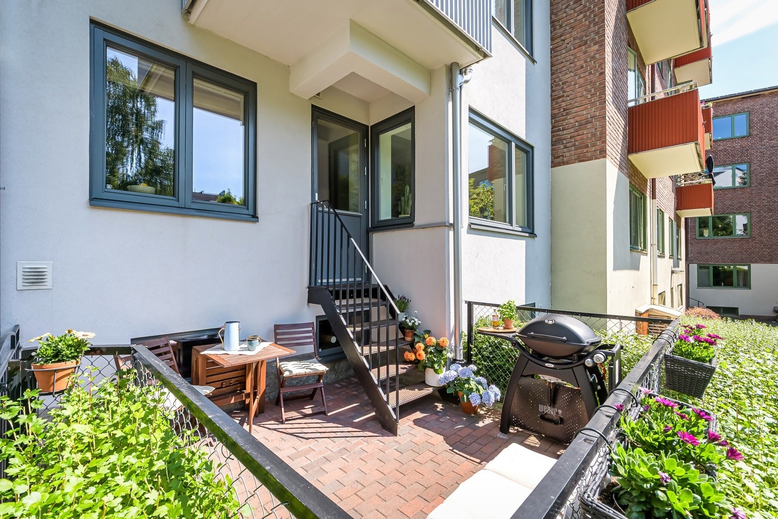 Uteplassen er pent belagt med belegningsstein, omkranset av en tett og frodig hekk som gir både skjerming og en lun, grønn atmosfære. Galleribilde