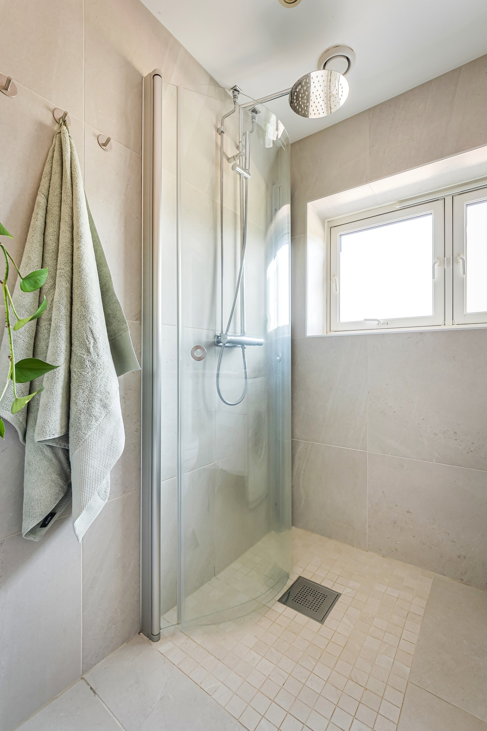 Dusjsonen er utstyrt med innfellbare glassdører og vegghengt dusjarmatur med både regnfallsdusj og hånddusj - en elegant og funksjonell løsning. Galleribilde