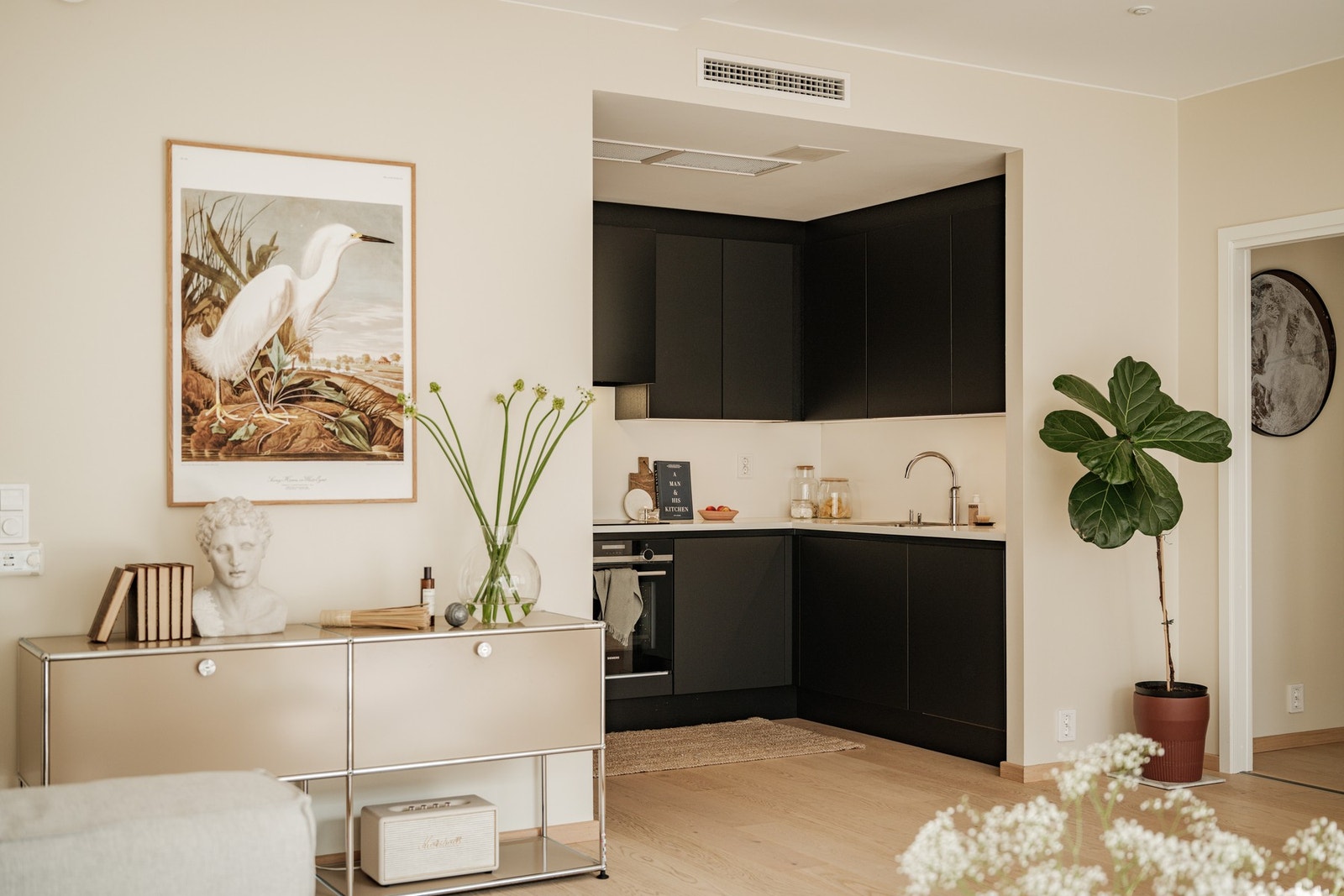 Leiligheten har et moderne og funksjonelt kjøkken med glatte, mørke skapfronter som utgjør en lekker og moderne kontrast mot den ellers lyse og luftige estetikken i rommet. Galleribilde