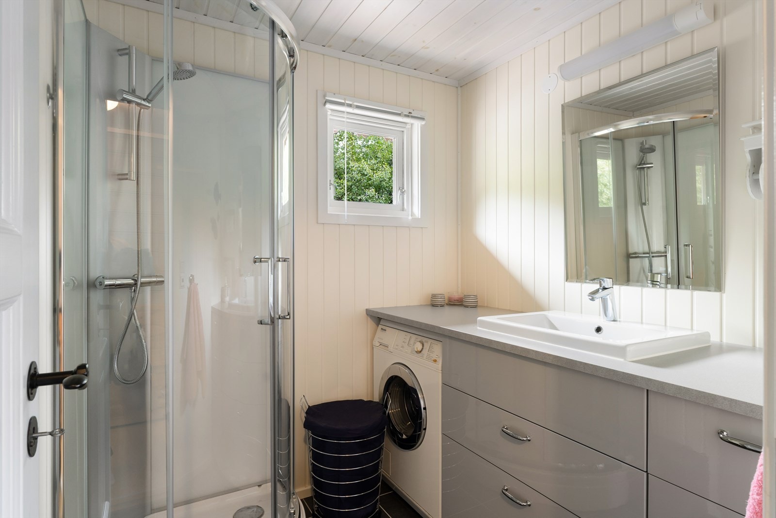 Badet ble pusset opp i 2019, og er praktisk med dusj, servant i skuffeinnredning og opplegg for vaskemaskin. Galleribilde