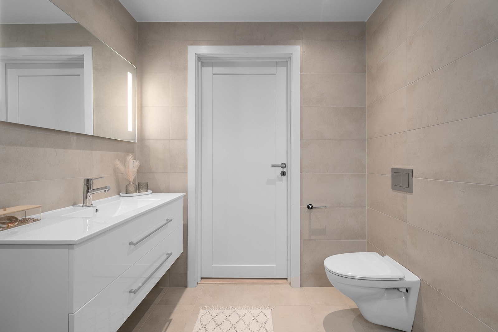 Badet har vegghengt toalett, stilrene overflater og en stor servant. Galleribilde