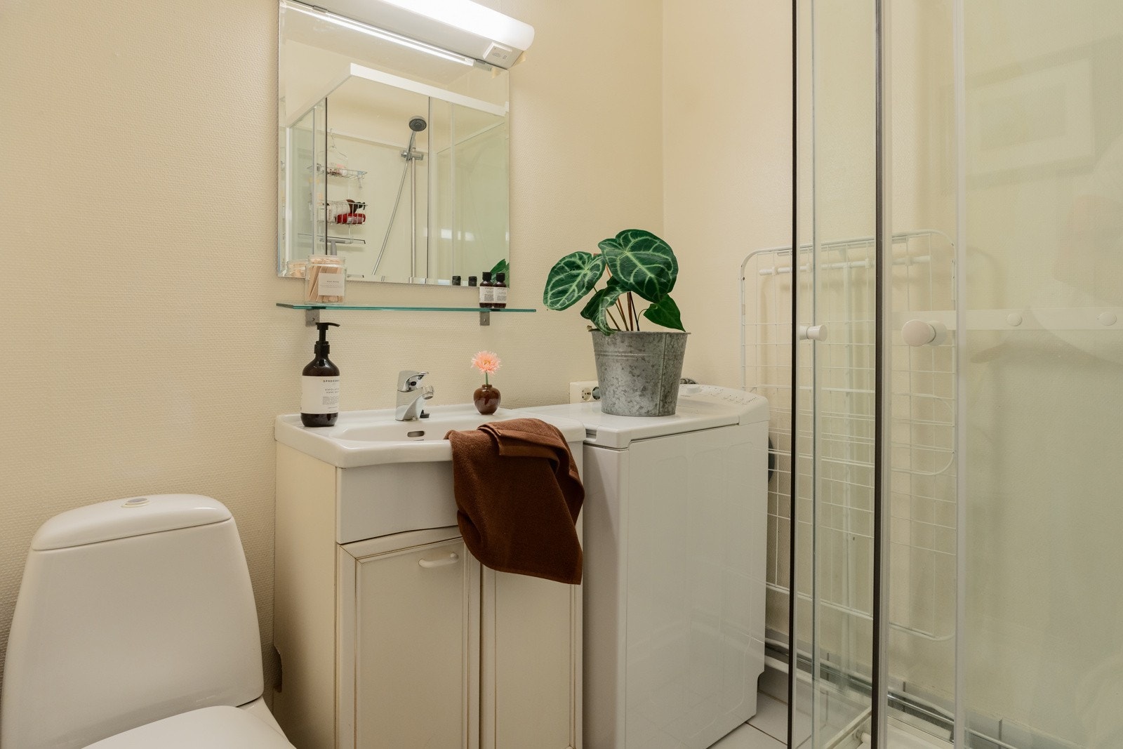 Badet byr på servantskap med glatte, folierte fronter og heldekkende servant. Speilskap og lysarmatur på vegg over servant. Til slutt er det dusj, toalett og opplegg for vaskemaskin. Galleribilde