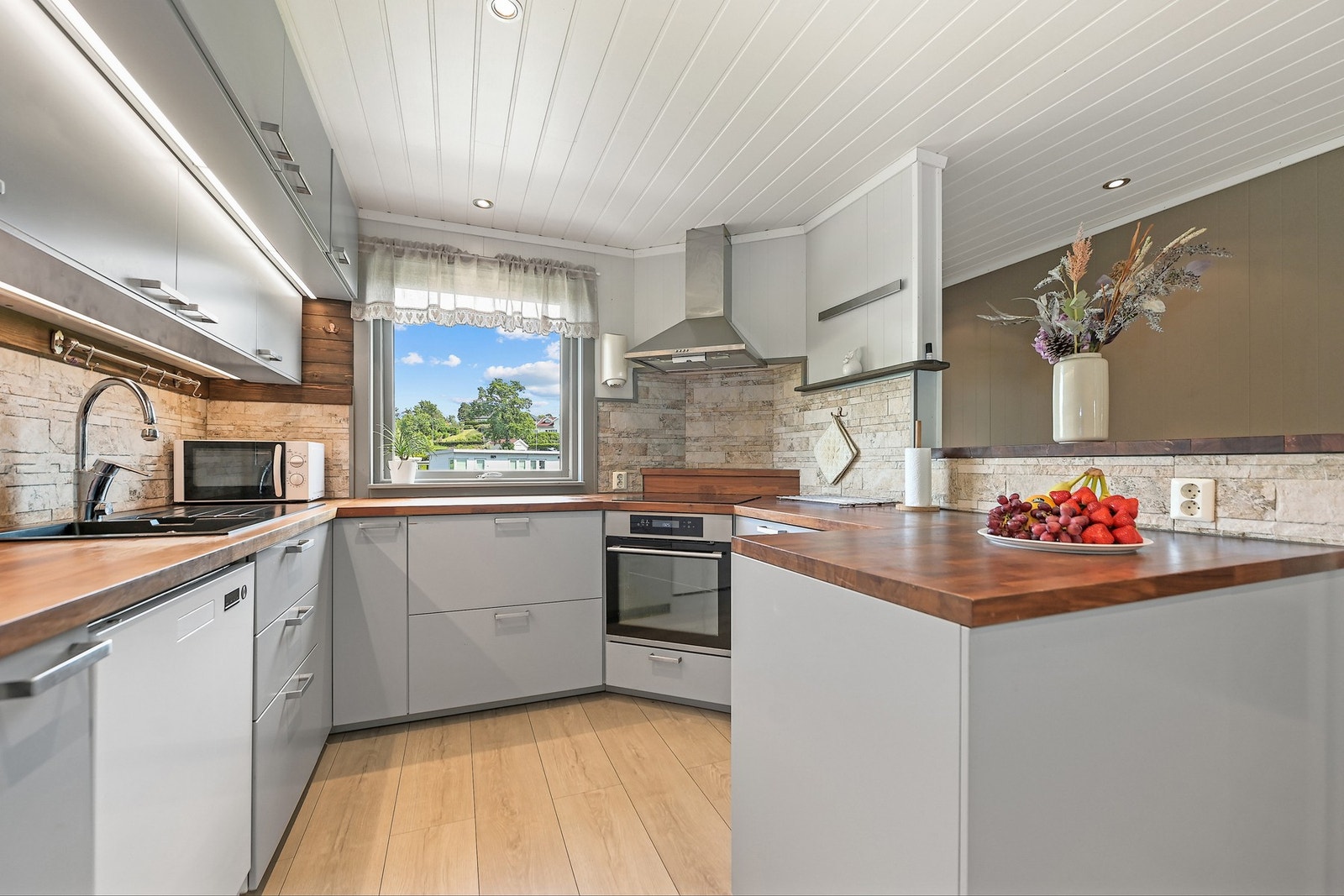 Kjøkkenet er innredet med slette fronter og heltre benkeplate. Integrert komfyr og platetopp, underbygget oppvaskmaskin og frittstående kjøl/fryseskap. Galleribilde