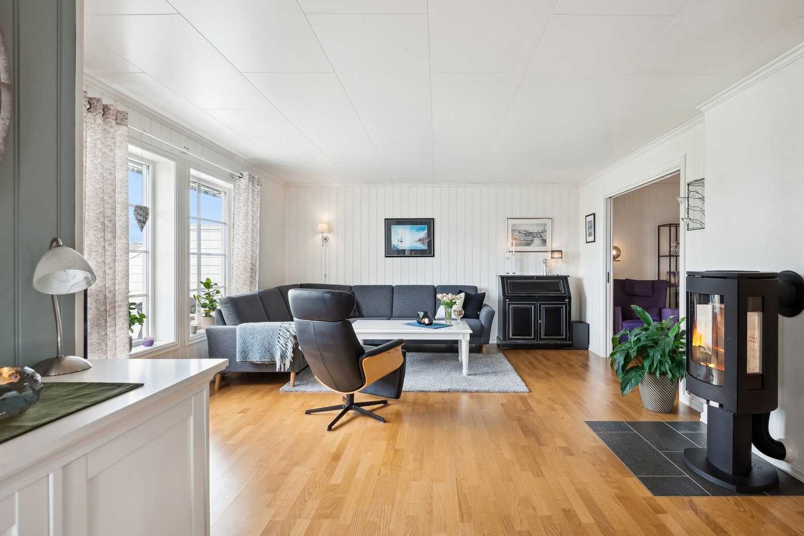 Romslig stue med parkett på gulv og vegger med malte plater. Galleribilde