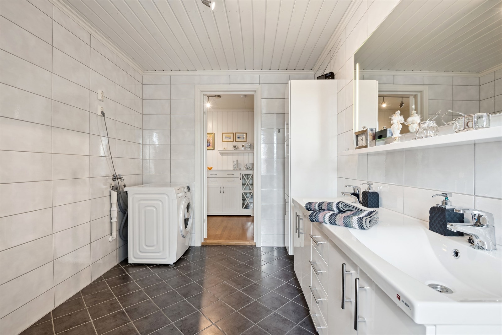 Innredningen består av en moderne servantseksjon med to nedfelte servanter, vegghengt toalett, og et praktisk dusjkabinett. Det er varmekabler i gulv. Galleribilde