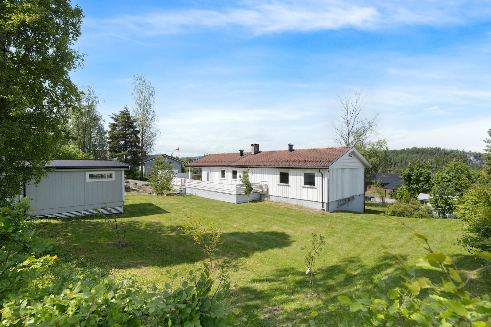 Tomten er pent opparbeidet med gressplen og diverse beplantning. Galleribilde