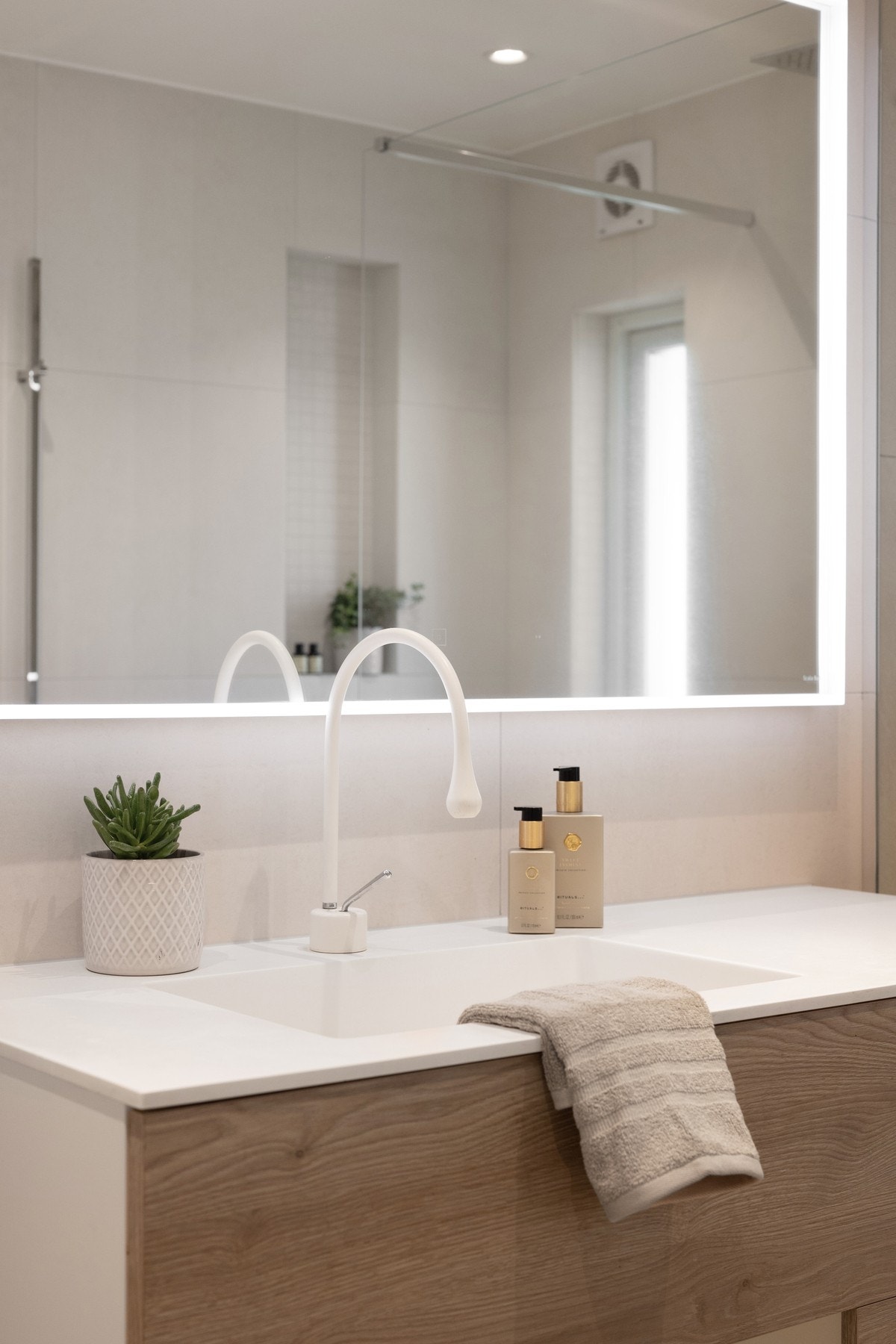 Videre er badet innredet med vegghengt toalett og servant med underskap. Downlights i malt himling sørger for god belysning. Galleribilde