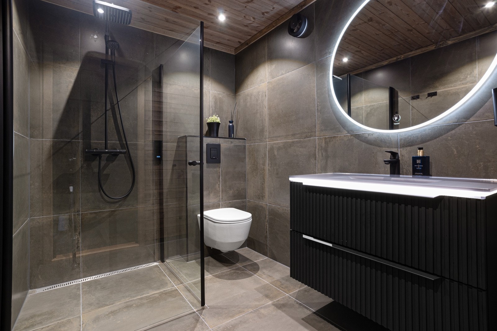 Bad i kjeller har flislagte gulv og vegger. Videre er det innredning med nedfelt servant, speil med lys, vegghengt toalett og dusjnisje Galleribilde