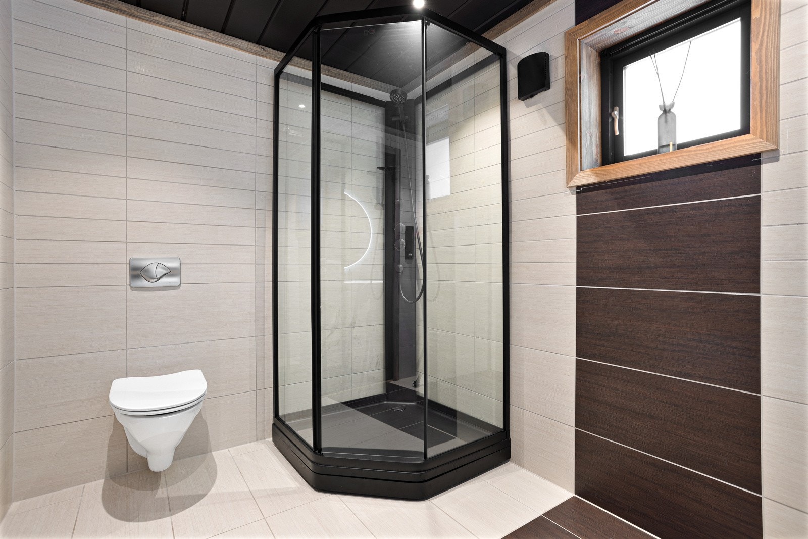 Gjestebadet i hyttas hovedetasje inneholder innredning med servant, speil med lys, dusjkabinett og toalett Galleribilde