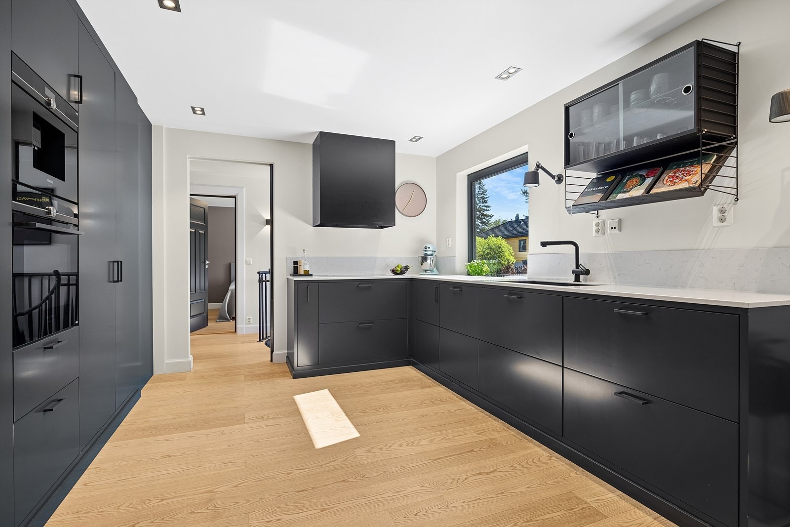 Hel vegg med takhøy innredning med kaffemaskin og kombiovn på vegg. Galleribilde