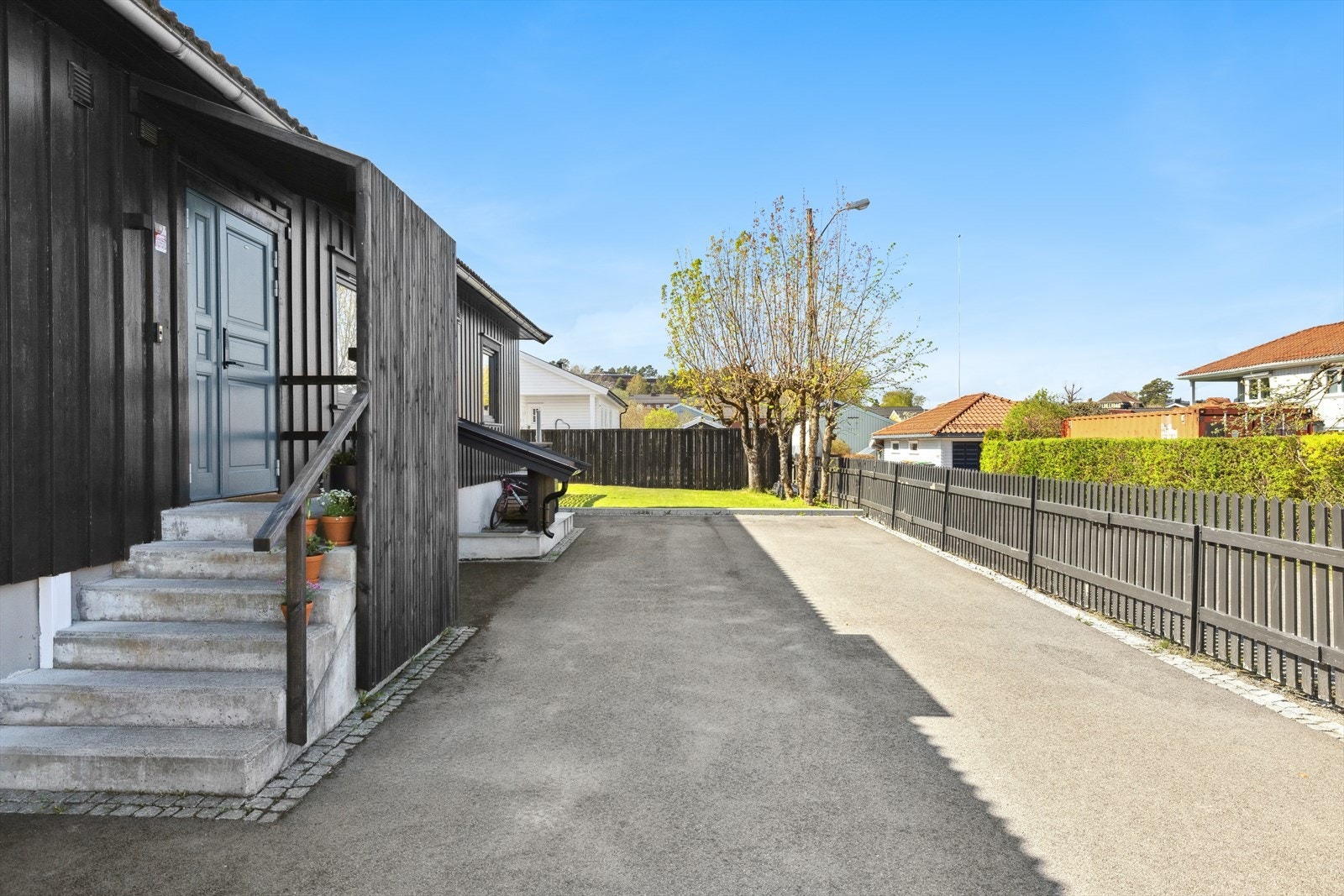 Asfaltert og inngjerdet gårdsplass med overbygget inngangsparti Galleribilde